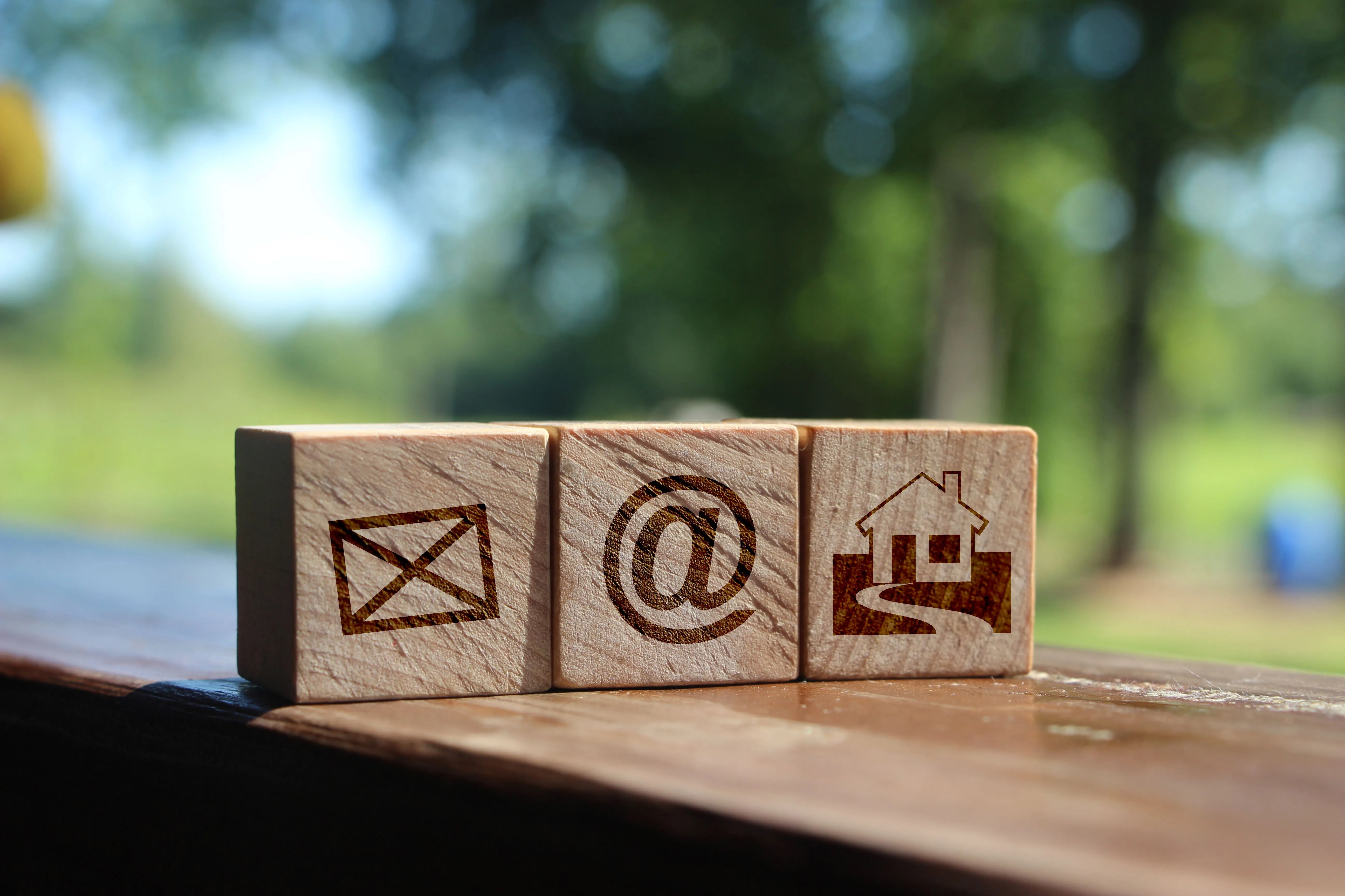 Three wooden blocks with communication icons: email, at symbol, and home