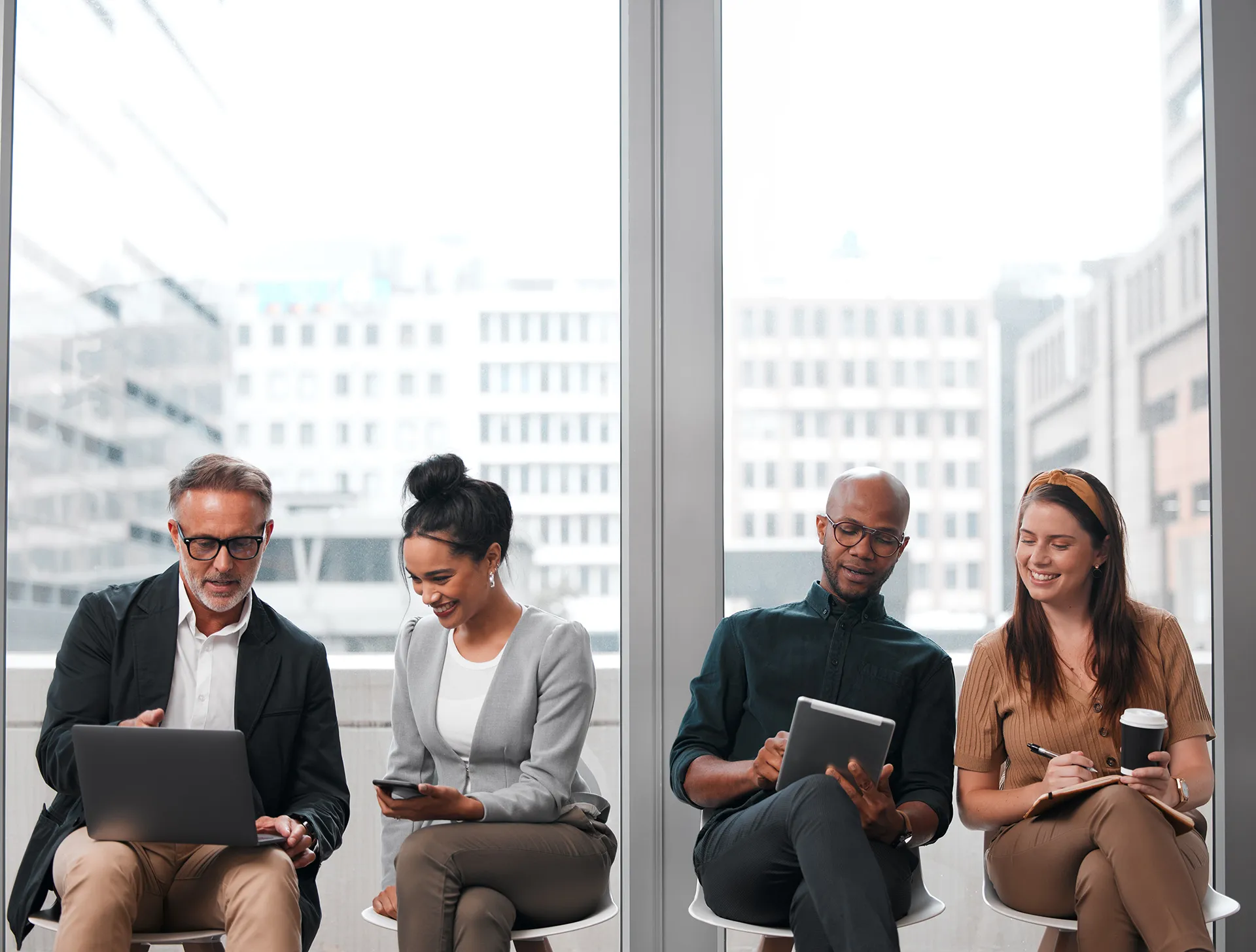 Diverse business professionals working together with digital devices near office windows