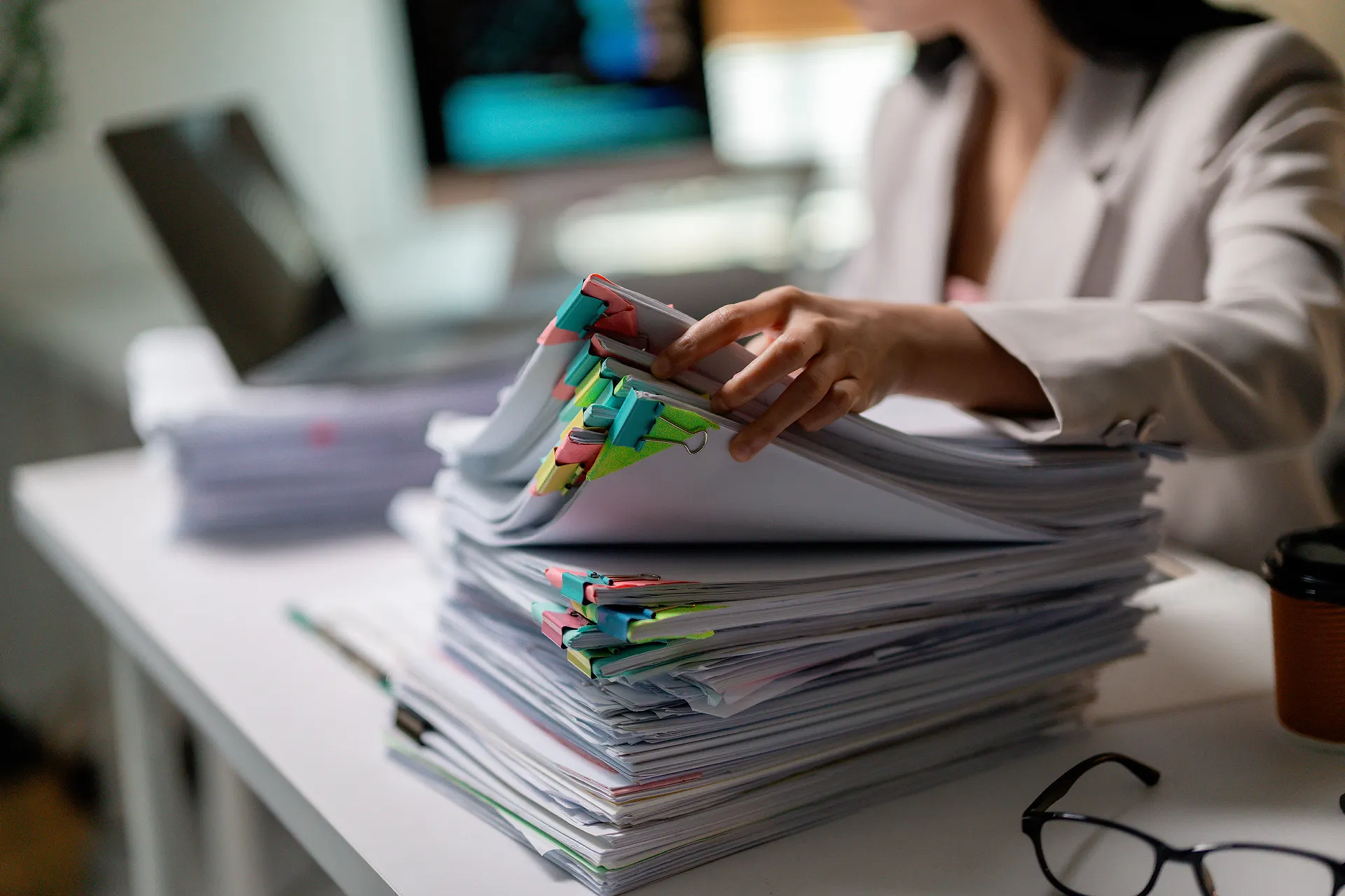 Hand organizing large stack of documents with colorful file tabs