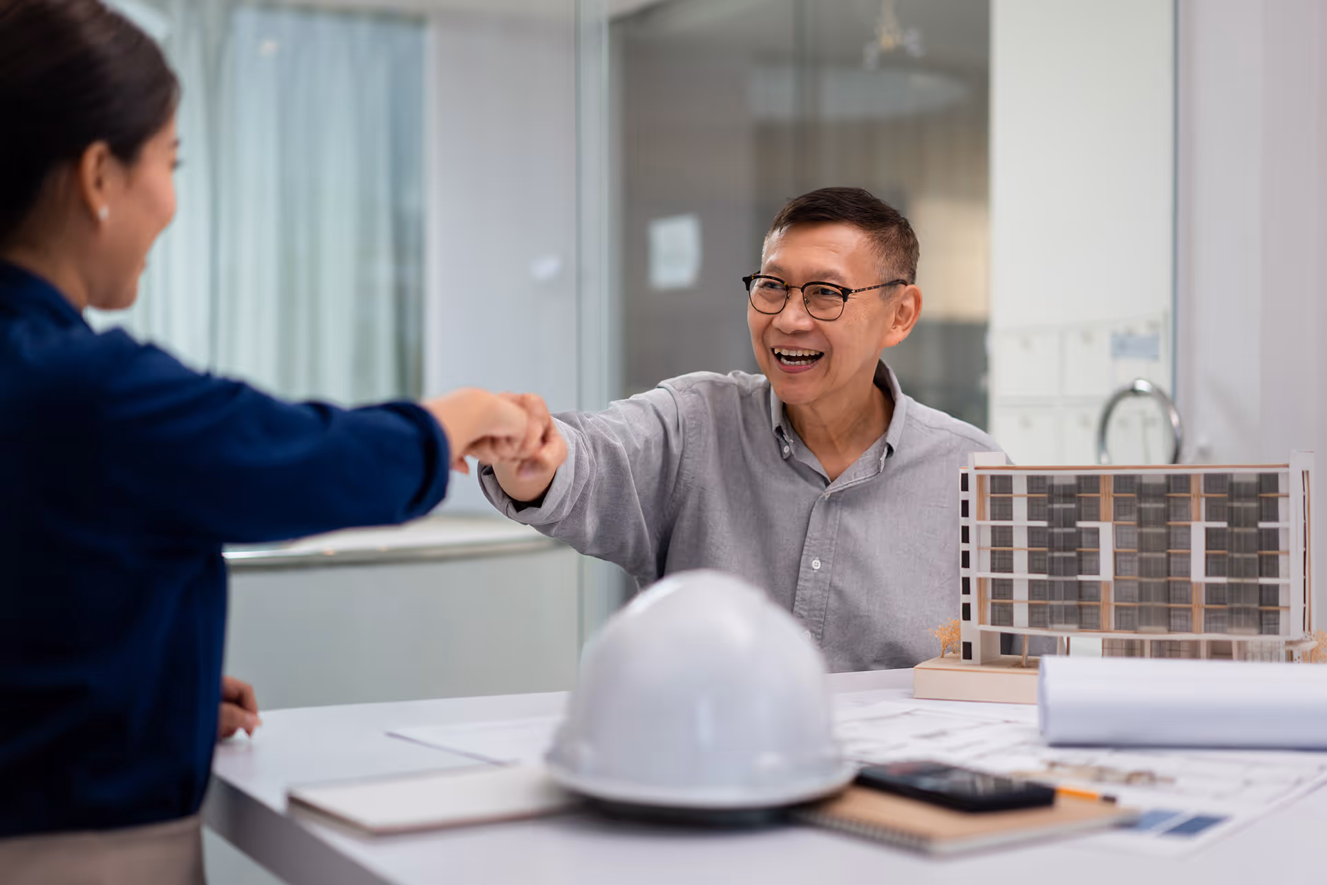 Architects discussing building model in bright office with excitement