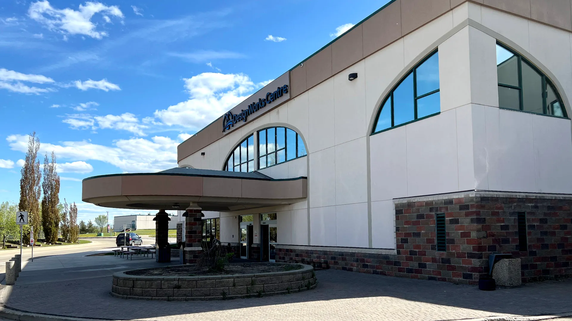 Modern community center with arched windows under blue sky with clouds