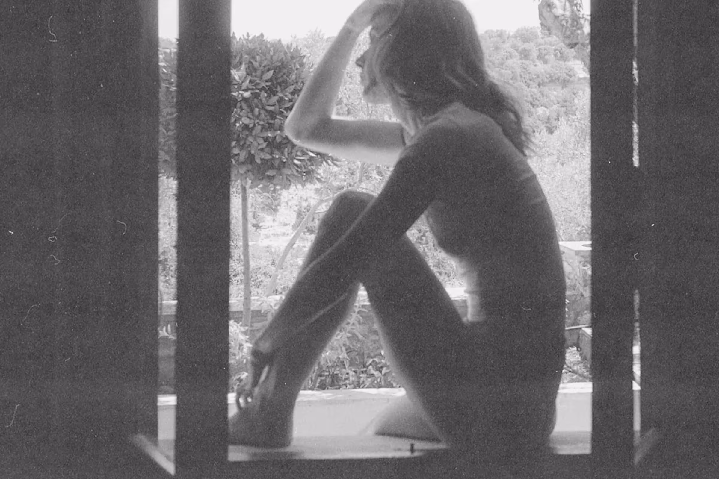A woman sitting in a window wondering how soon she can get tested for STDs after unprotected sex 