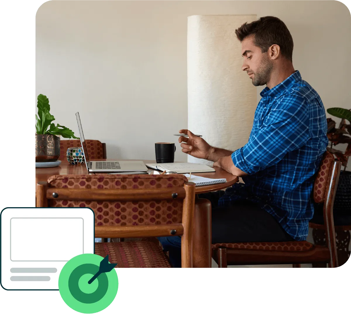Man sitting at a dining table working on a laptop with notebook reviewing protocols.