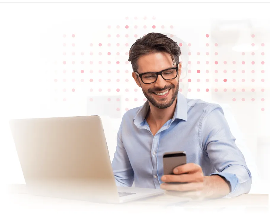 Smiling man in blue shirt looking at smartphone while carrying shoulder bag.