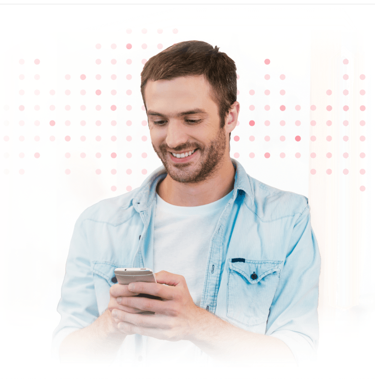 Smiling man in blue shirt looking at smartphone while carrying shoulder bag.