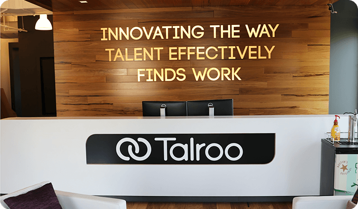 Reception area with Talroo logo and wooden wall text: Innovating the way talent effectively finds work.