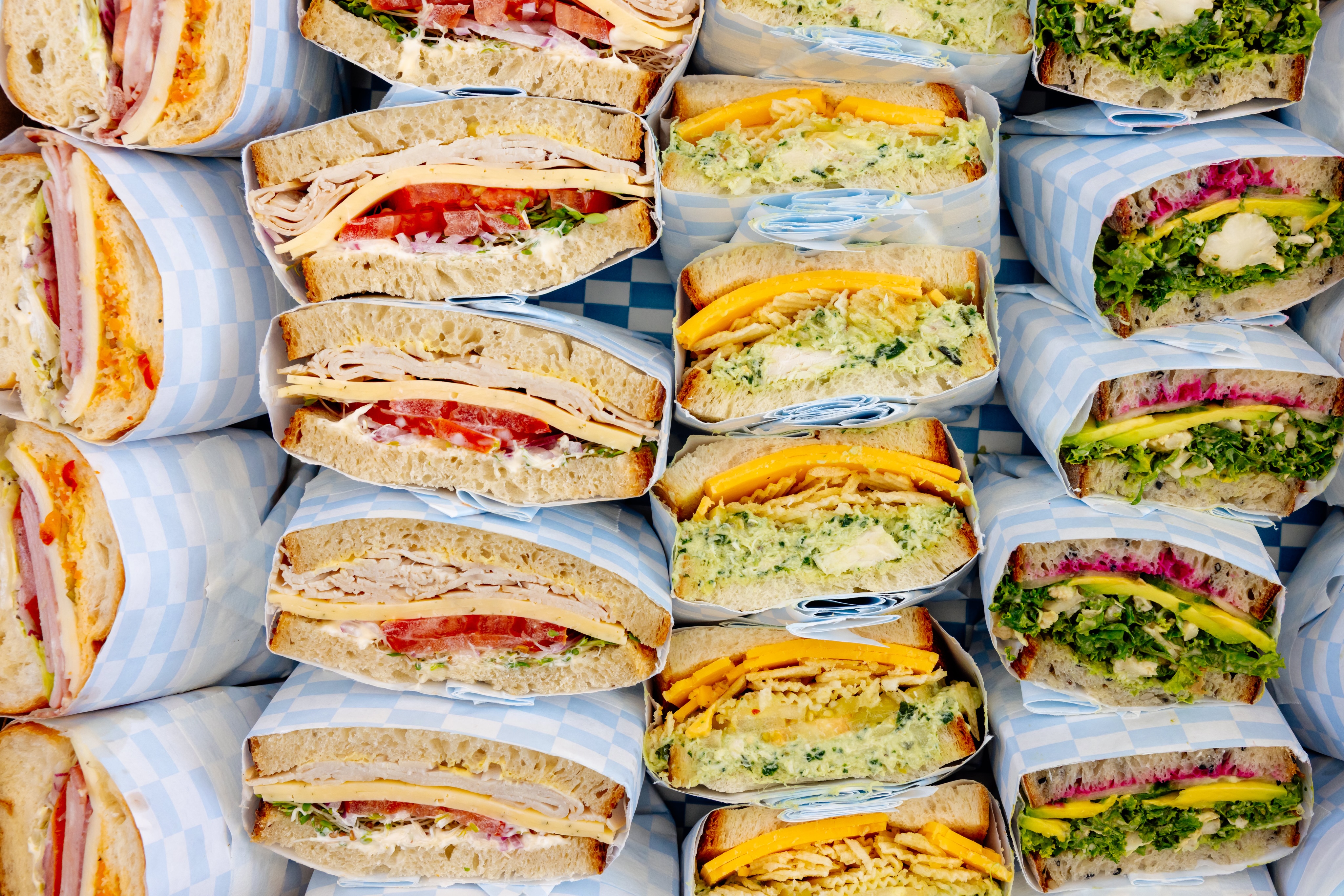Rows of Swedish Hill sandwiches wrapped in blue-and-white checkered paper, ready for catering