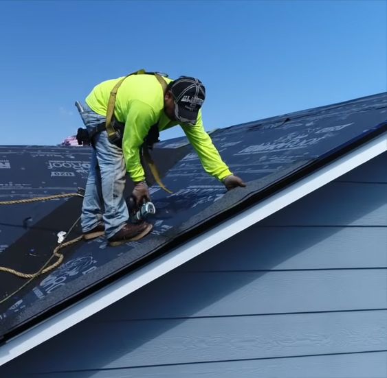 A worker carefully applies roof underlayment, layering waterproof material across a residential roof to enhance durability and protection.