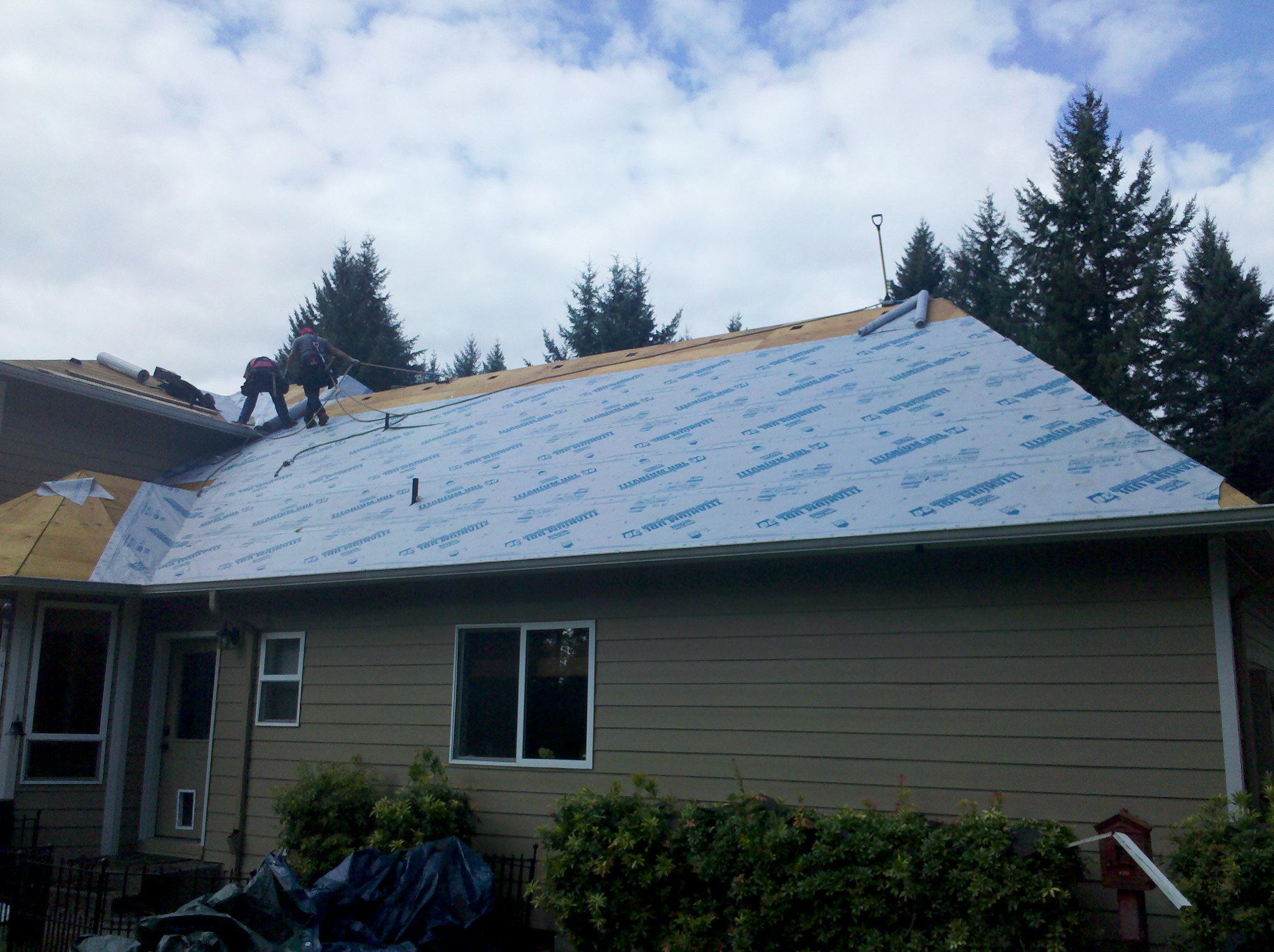 A roof mid-process, layered with protective underlayment sheets.