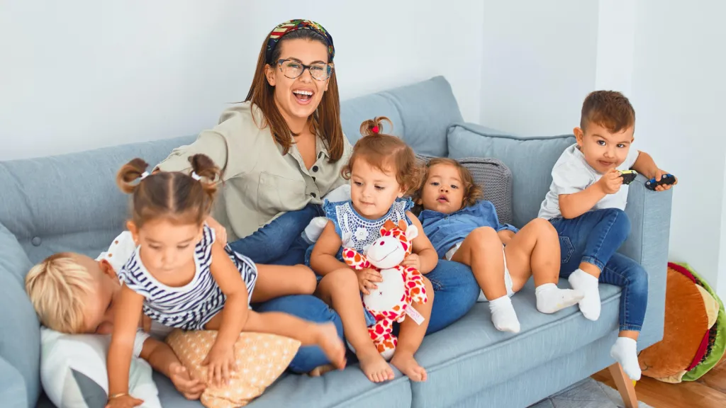 woman sitting on blue couch with kids on back