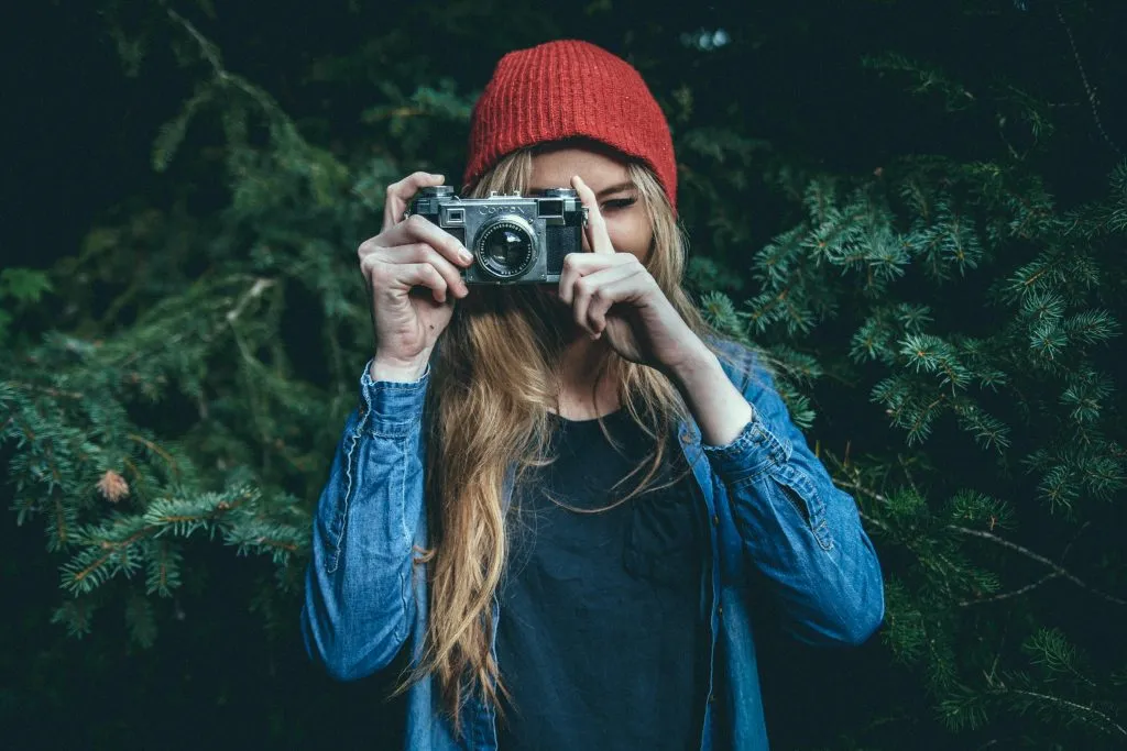 a woman holding a camera with her hands near her face