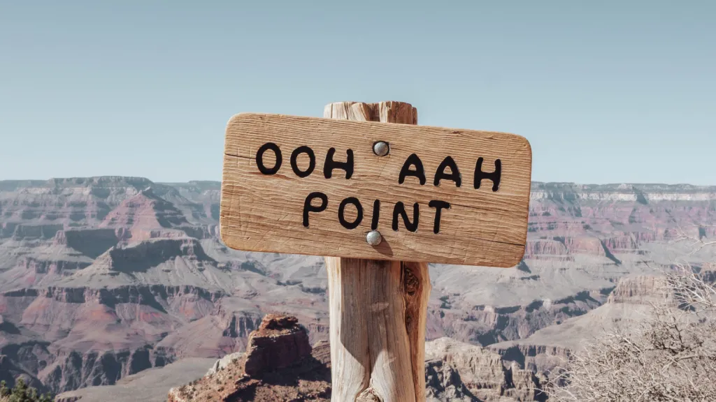 a sign near some mountains with a sky background