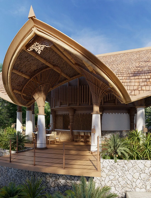 Outdoor view of a tropical wooden pavilion with a curved thatched roof supported by white columns, surrounded by lush greenery and a stone wall.
