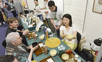 テーブル越しに抹茶を楽しむ日本茶イベントの参加者たち。