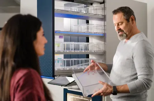 A man holding a clear plastic box with a woman standing next to him.