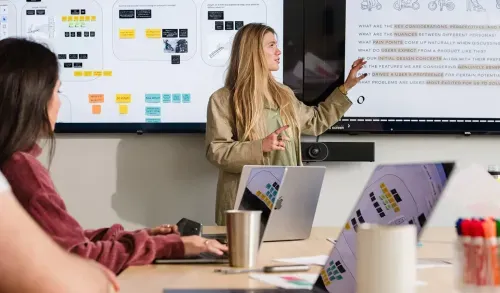 A woman giving a presentation in front of a laptop.