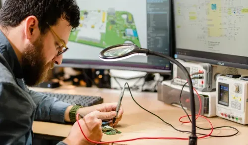 A man working on a computer with a magnifying glass.