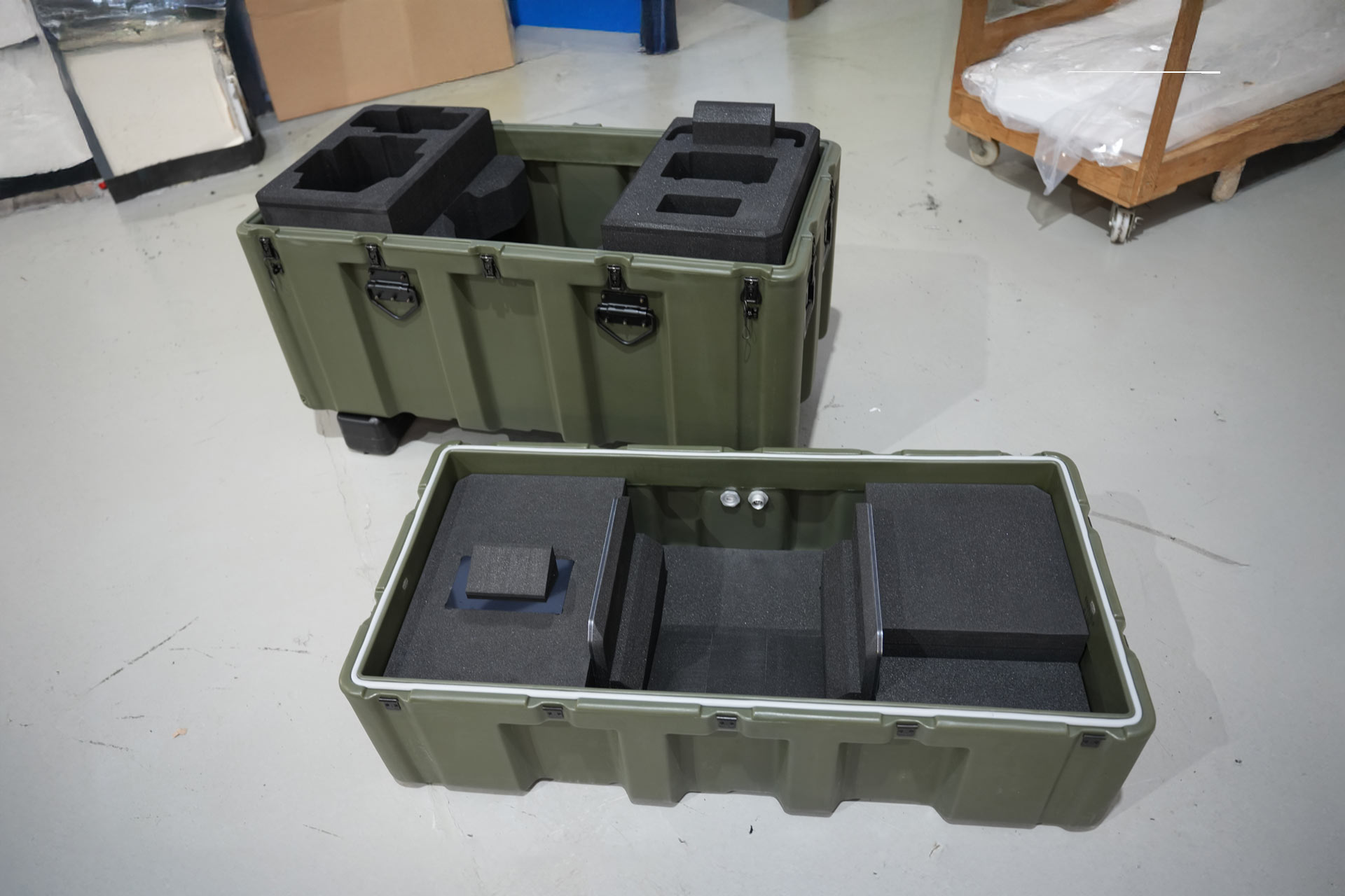 Green Peli-Hardigg transport cases with custom black foam inserts for secure military equipment protection