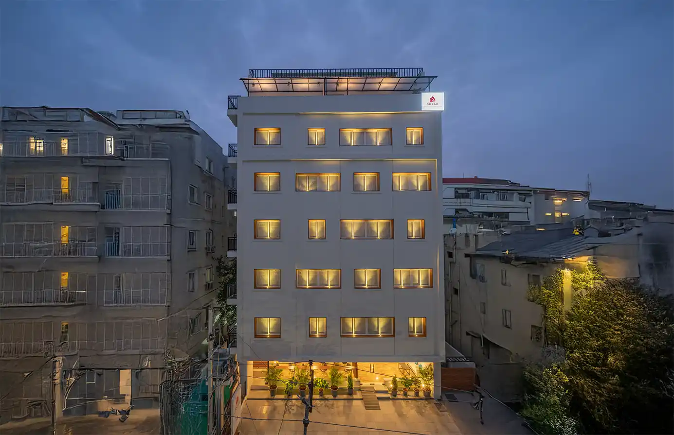 A frontal view of Skyla Studios & Suites located in Hitech City, Madhapur, Hitex, Kondapur, and Road No.45, Jubilee Hills. The well-lit elevation of the hotel building is set in the backdrop of an evening sky in Hyderabad.