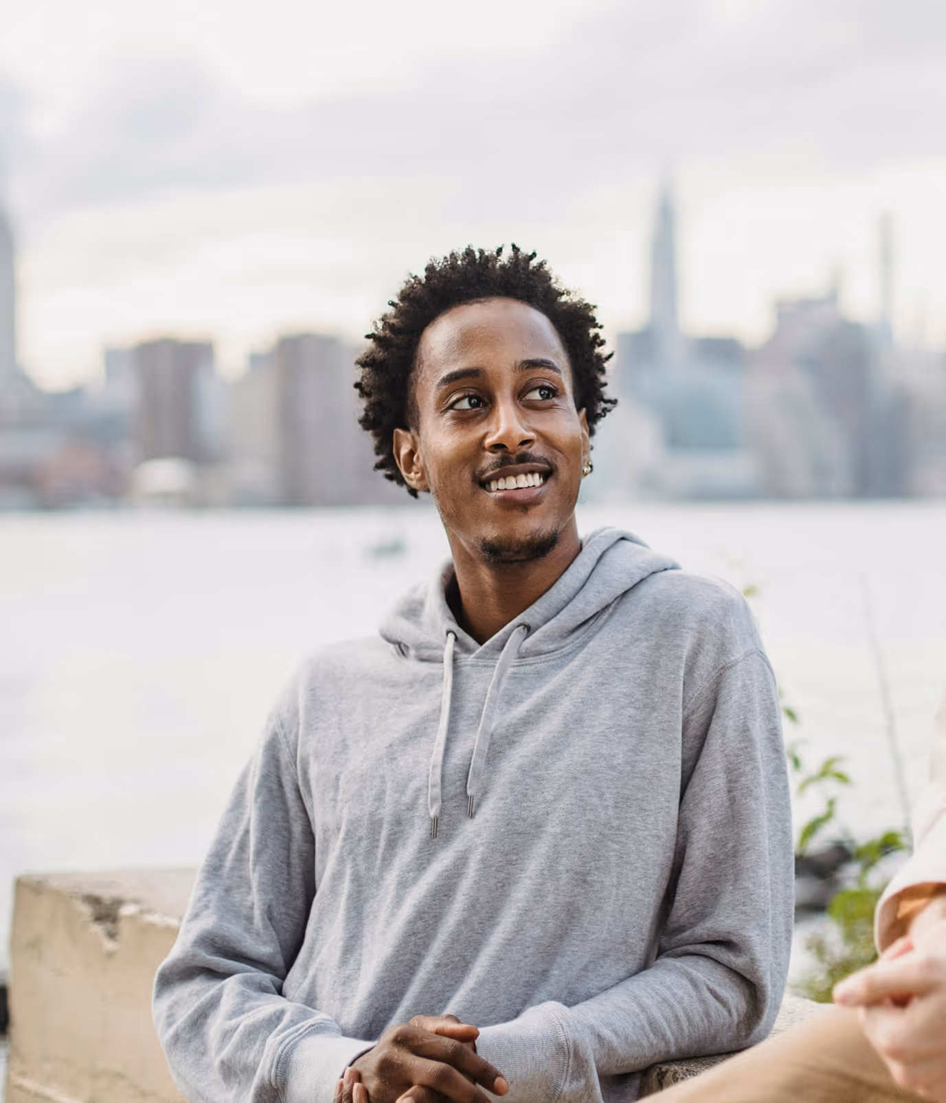 Man in grey jumper smiling to someone off camera.