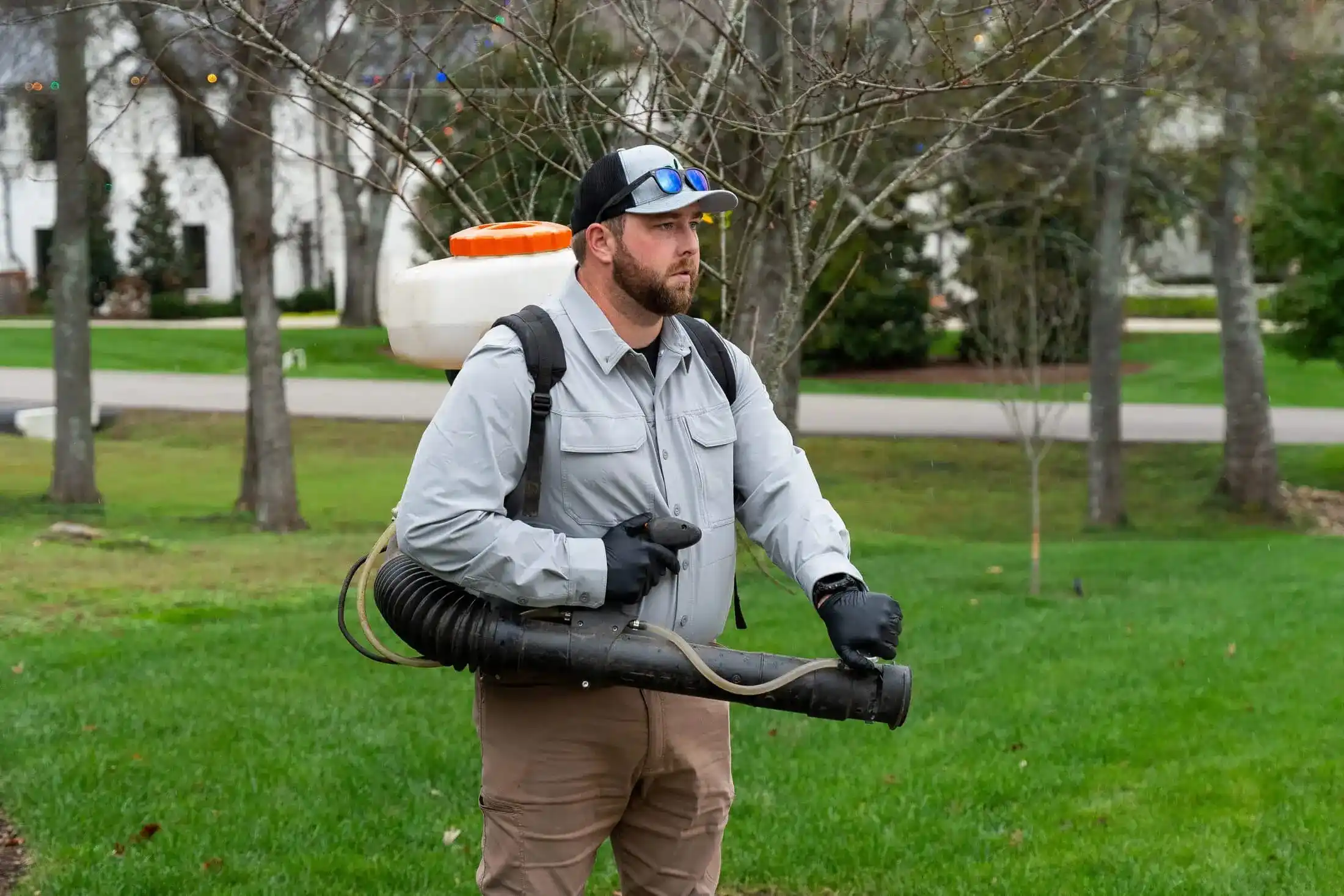 Veragreen technician using professional backpack sprayer equipment in public park or commercial green space
