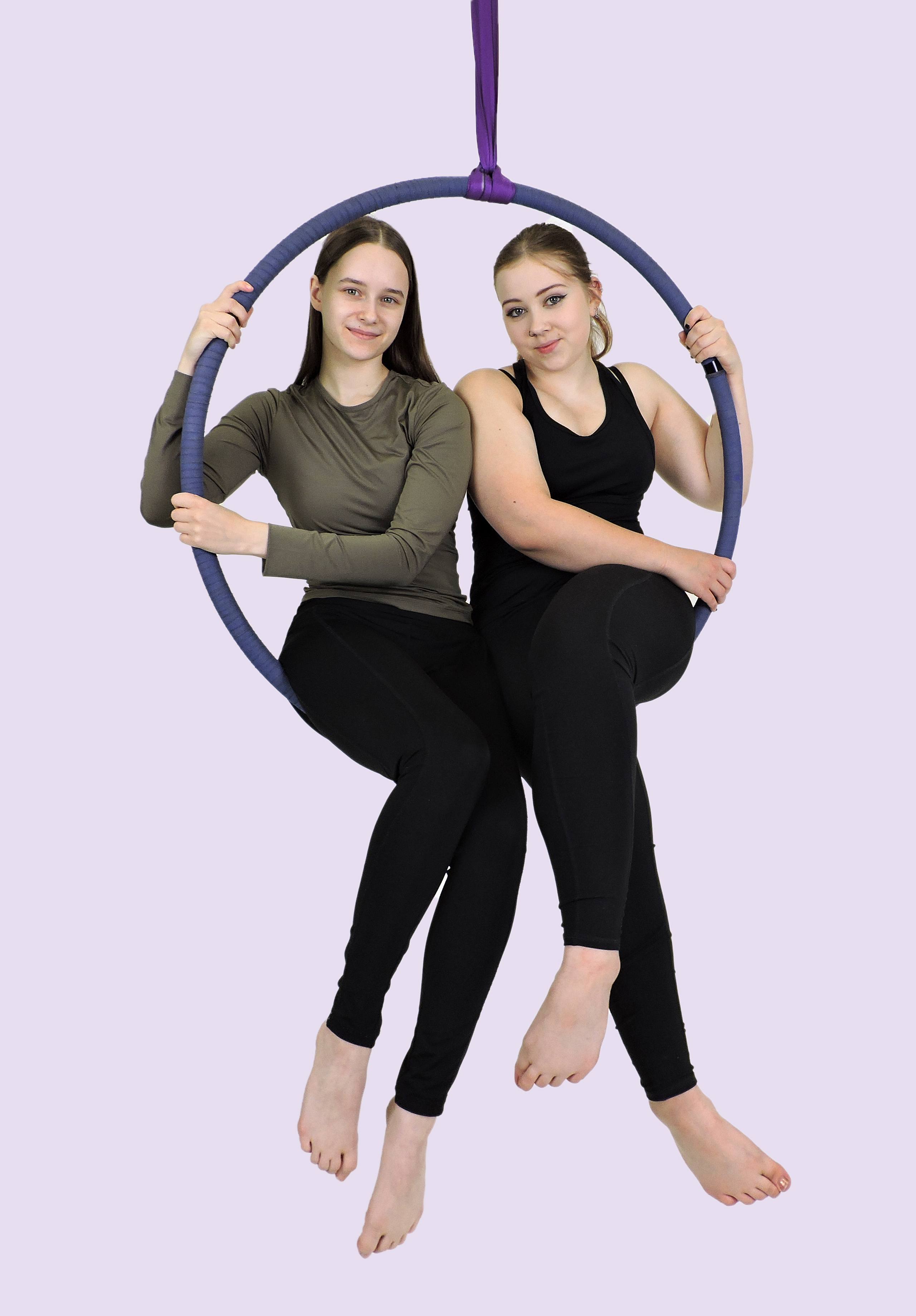 Naiset poseeraavat istuen ilma-akrobatiavälineillä.