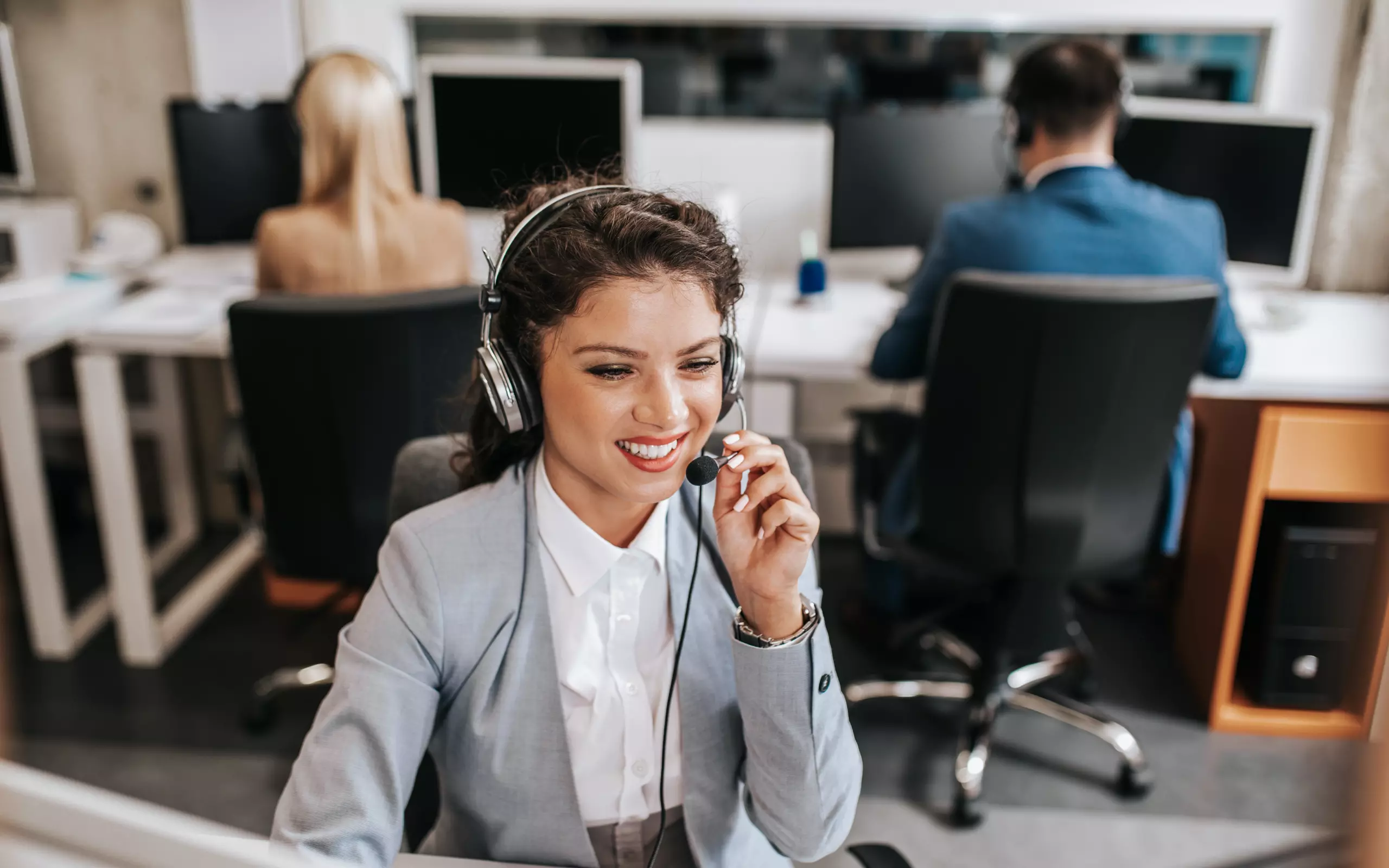 Zwei Mitarbeiter in einem Callcenter, die Headsets tragen und mit Kunden kommunizieren. 