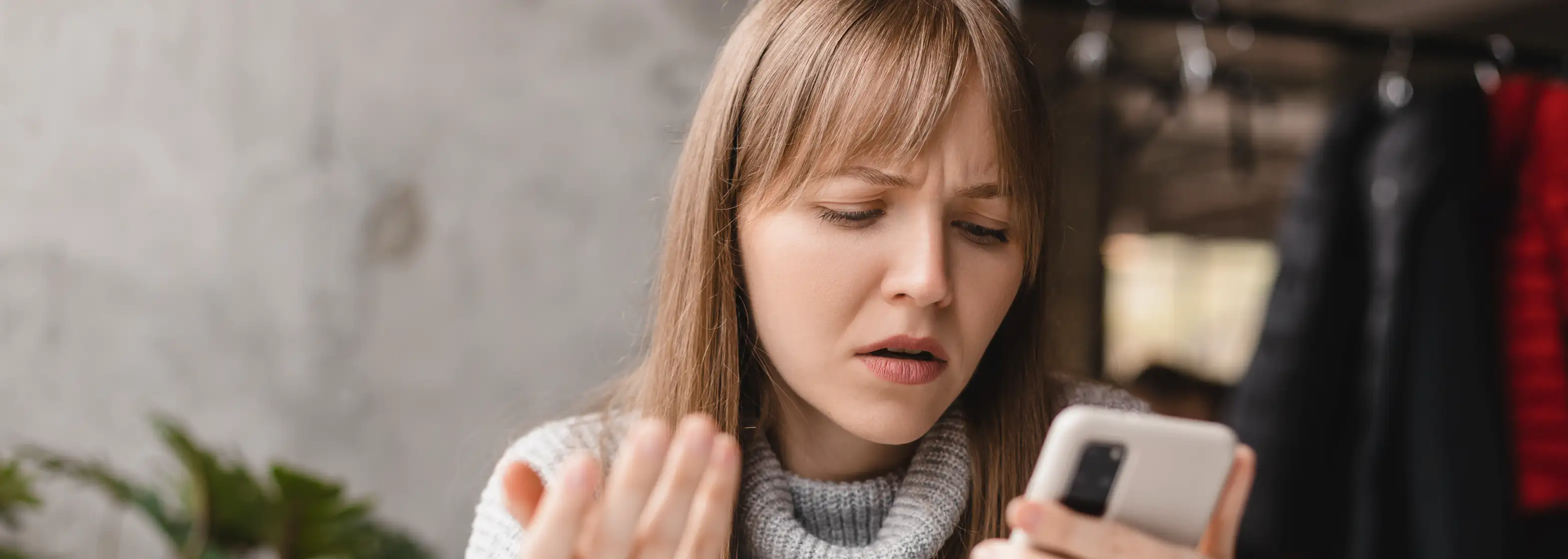 Kundin wirkt unsicher beim Blick auf ihr Smartphone während einer Serviceanfrage