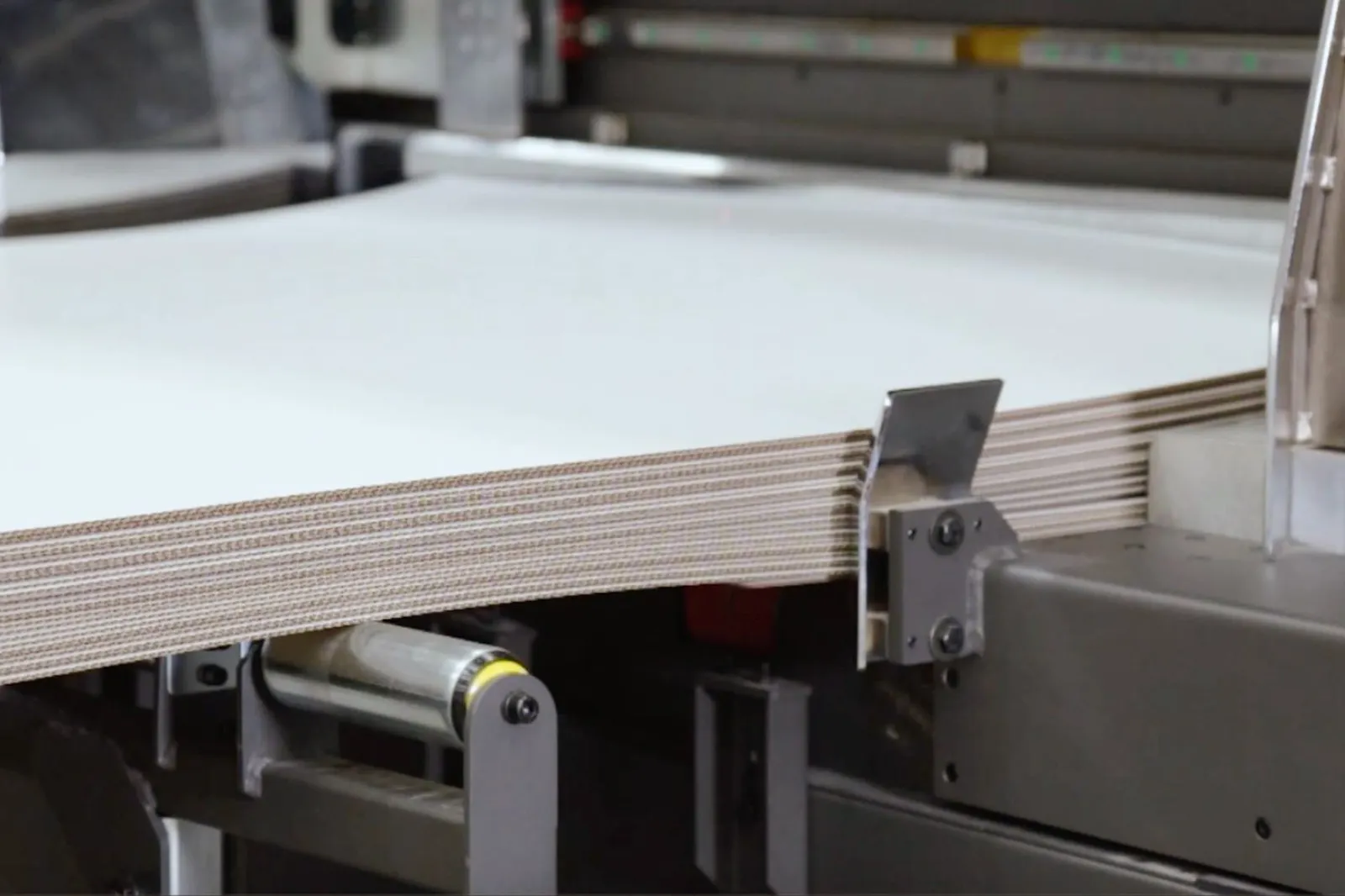 Close-up view of corrugated sheets stacked on an industrial machine.