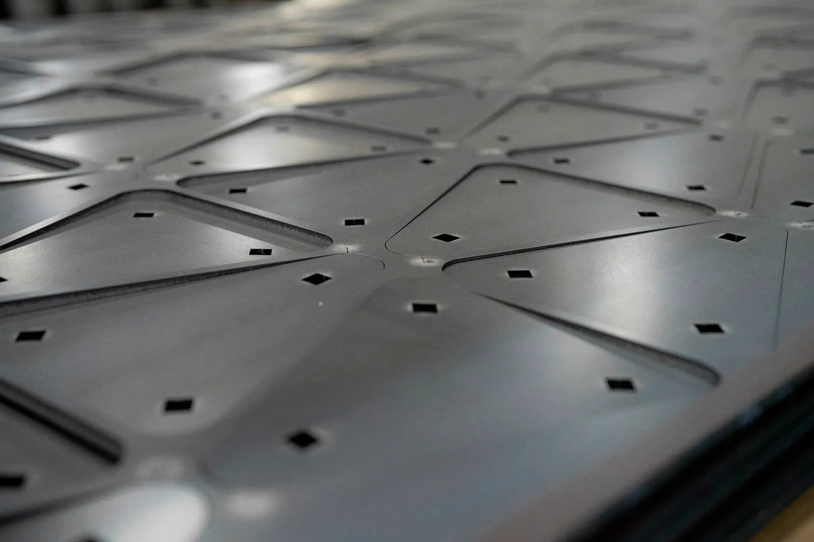 Close-up of a perforated metal plate, emphasizing the arrangement and size of the holes in the material.