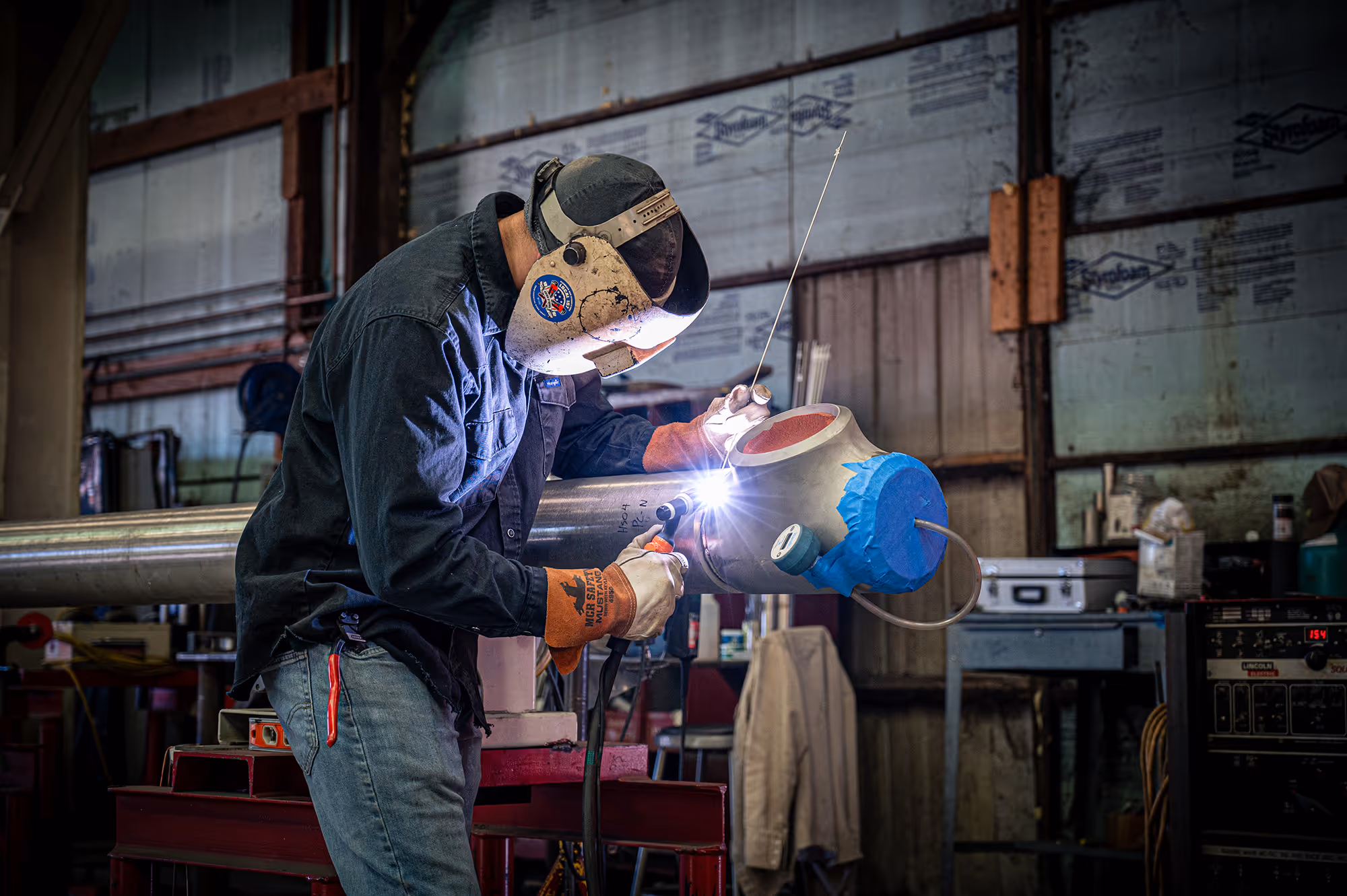 A Freitag employee welding together stainless steel piping.