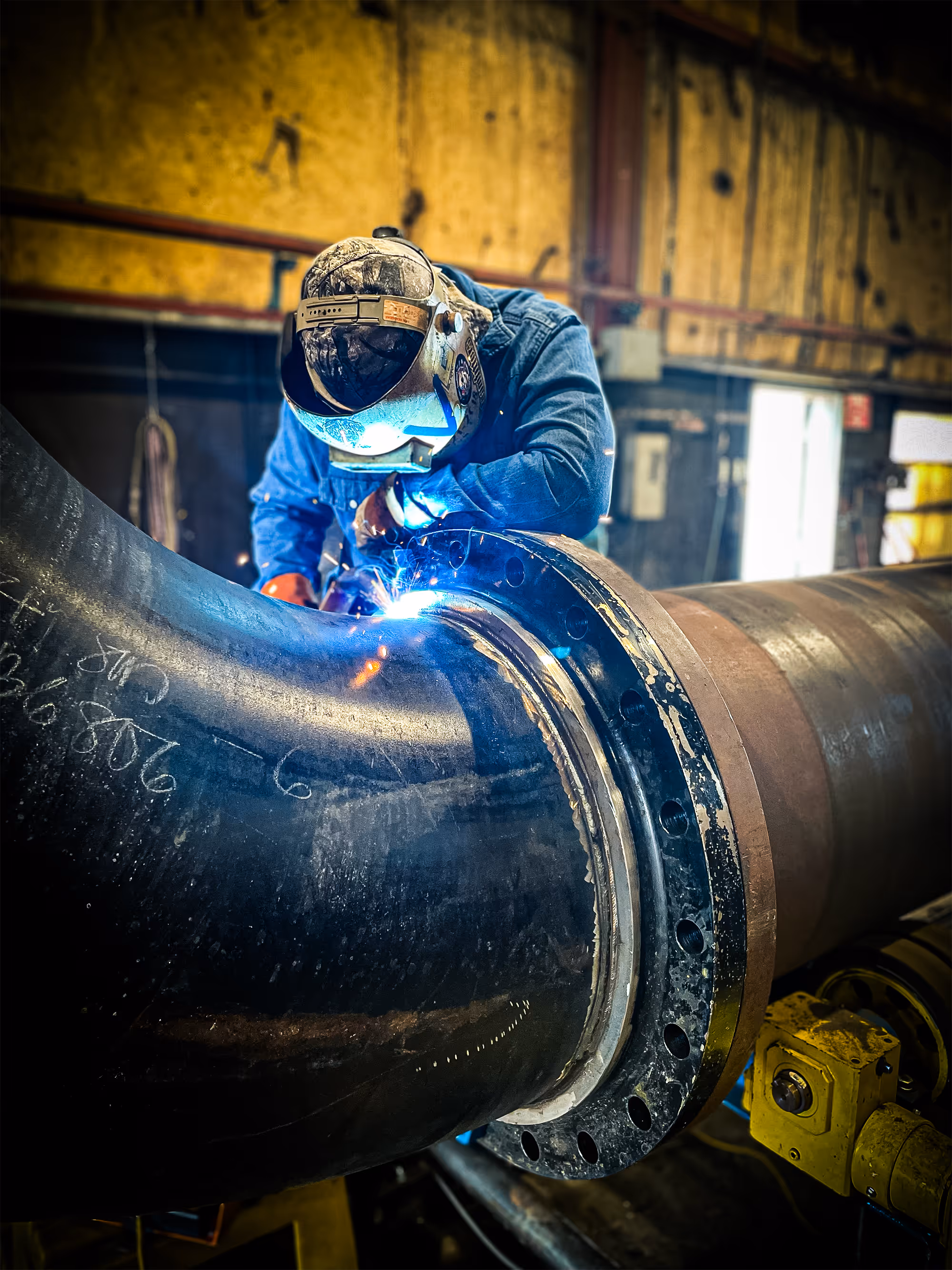 A Freitag-Weinhardt employee is welding a joint together on a piece of curved piping
