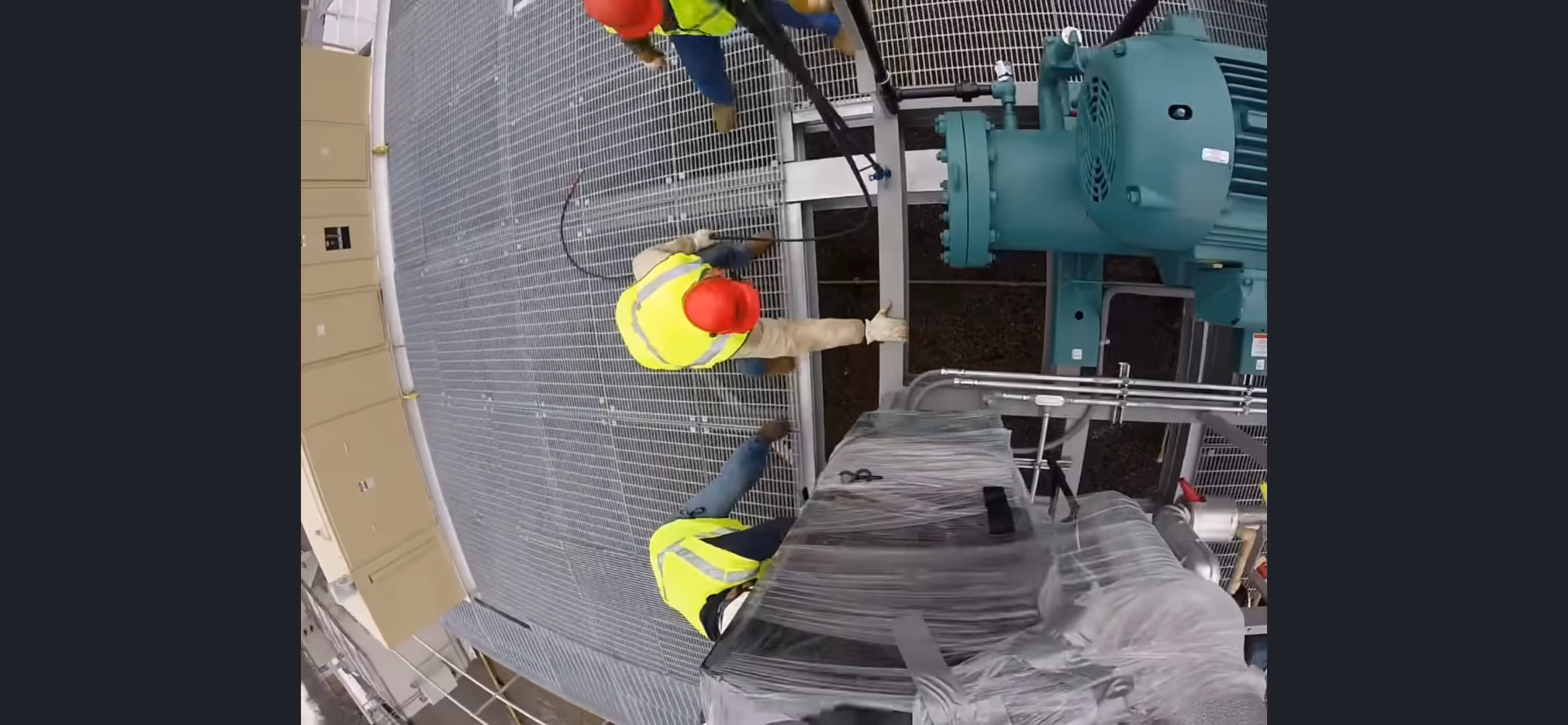 Freitag employees lowering a prebuilt HVAC component into place on a job site.