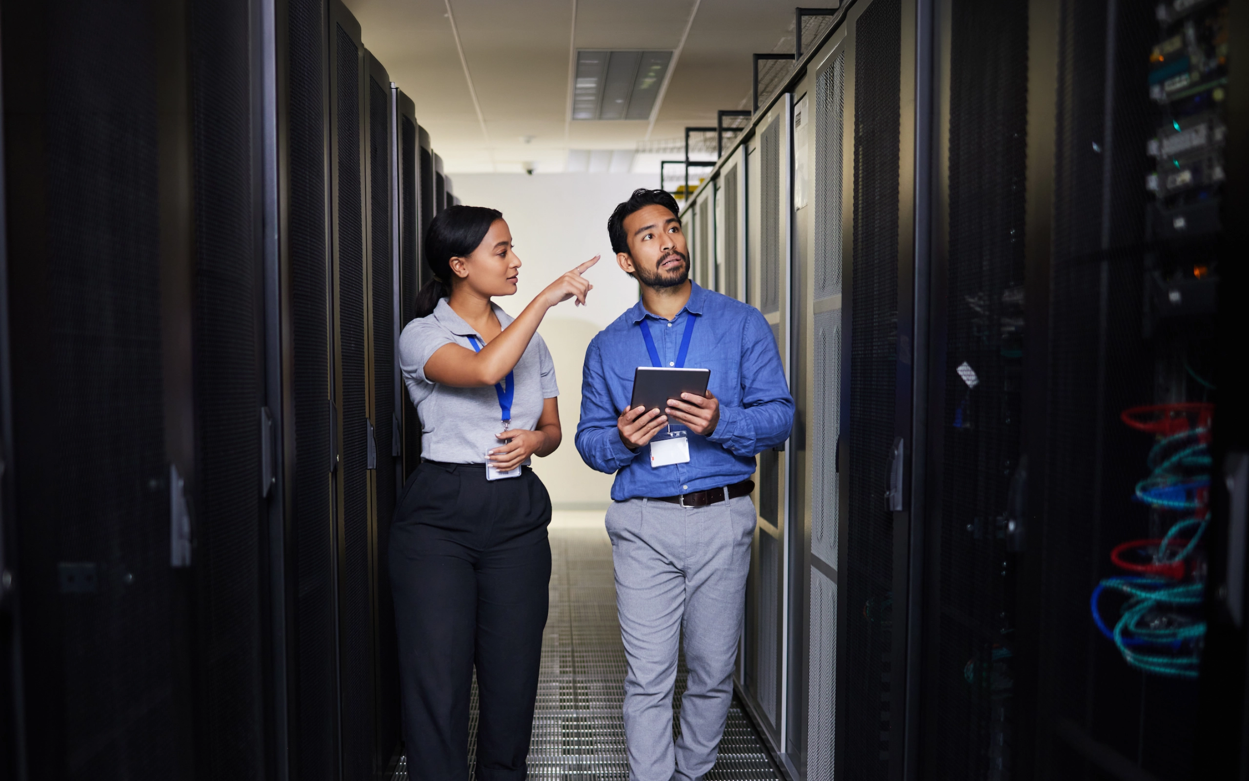 Technische Mitarbeitende prüfen Infrastruktur in einem Serverraum und dokumentieren Informationen vor Ort.