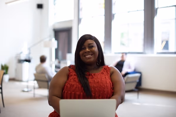 Plus size woman at work in bright, open office workplace with computer