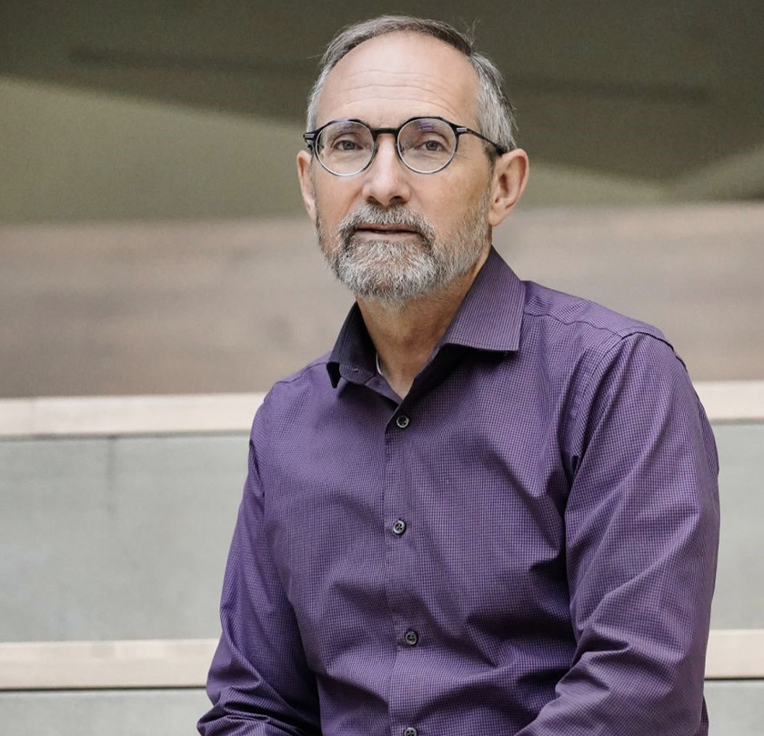 Design professional works in Engineering, portrait of man wearing purple shirt glasses.