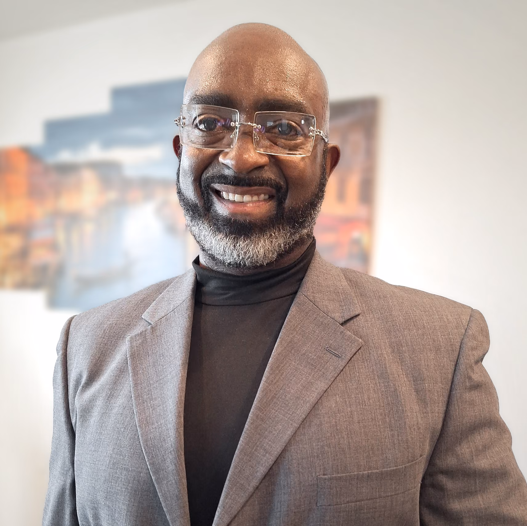 Christopher Robertson, smiling, wearing glasses, a black turtleneck, and a gray blazer.