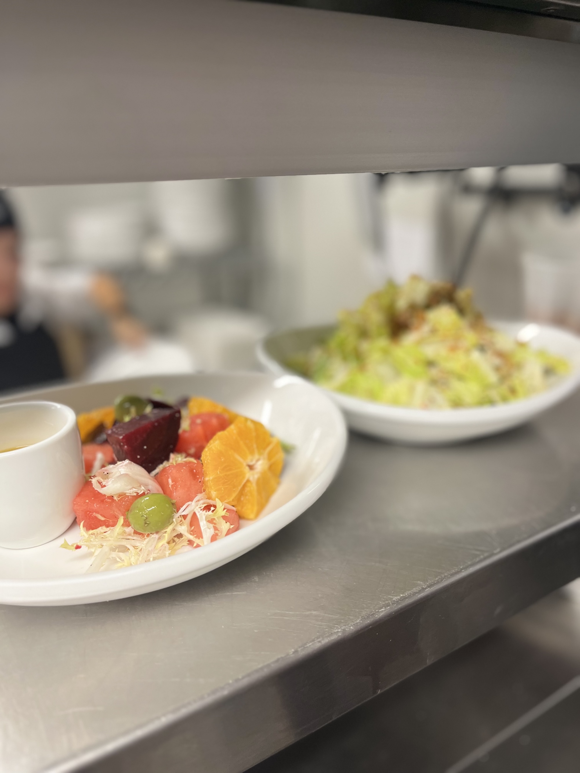 Two plates lined up- closer up plate has fruits and further plate is blurred