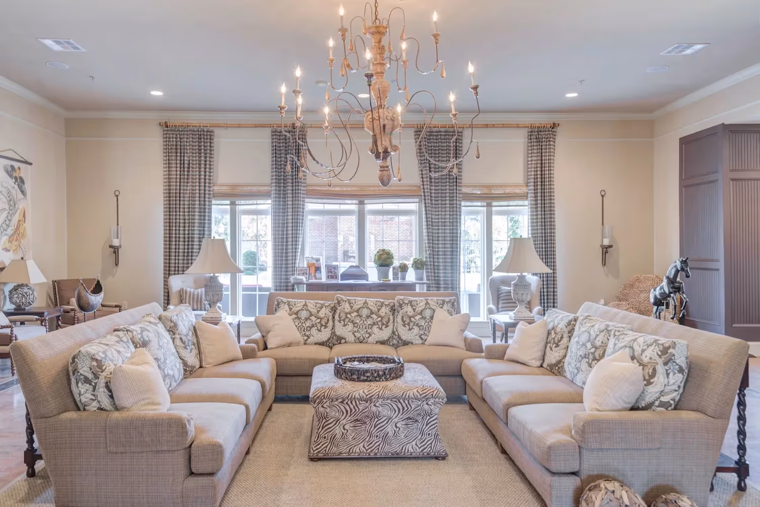 Elegant and spacious clubhouse lounge at The Grand at Lake Sheri in Valdosta, GA, with multiple seating arrangements and a grand chandelier.