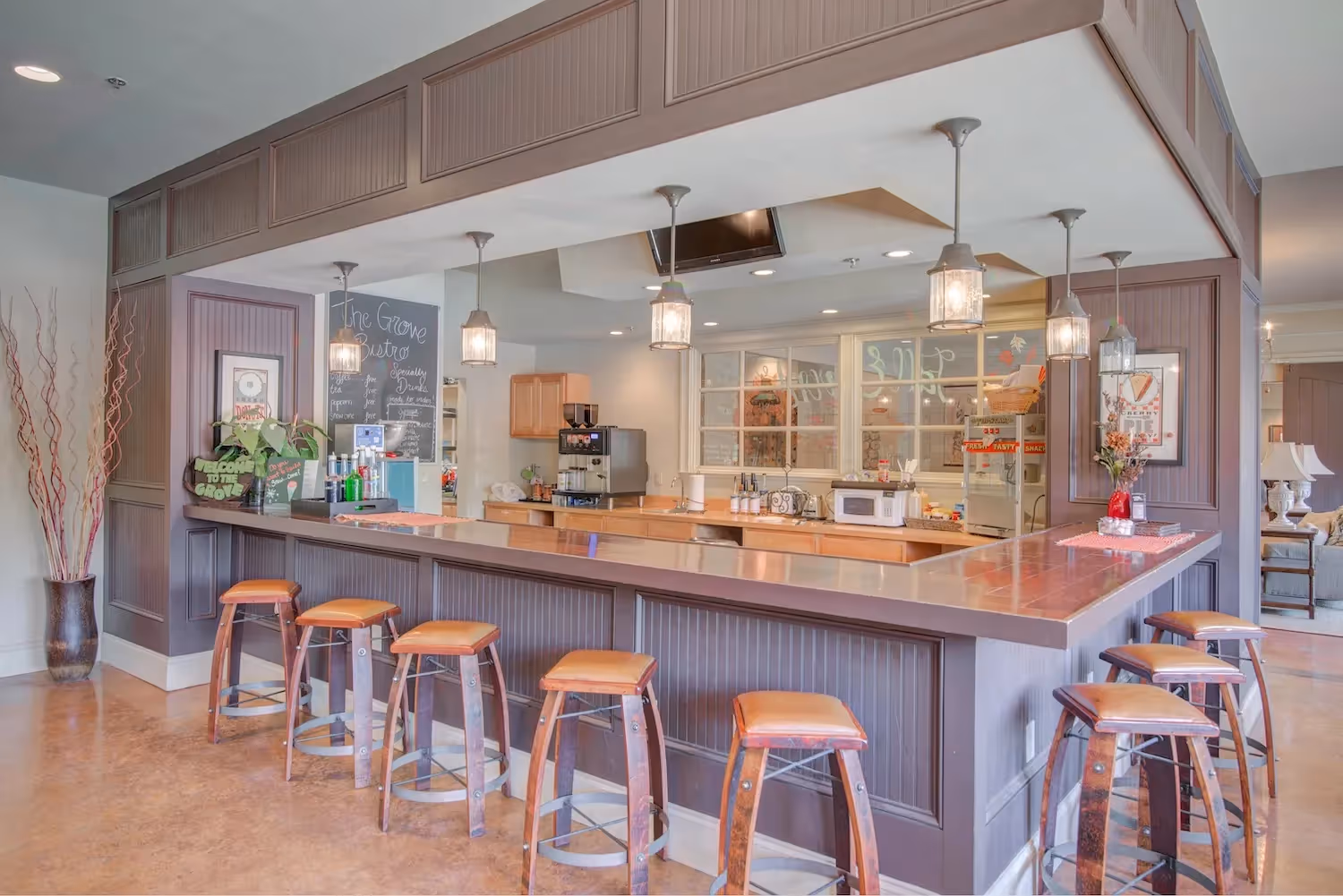 Resident coffee bar and lounge at The Grand at Lake Sheri in Valdosta, GA, featuring a long counter with bar stools and beverage stations.