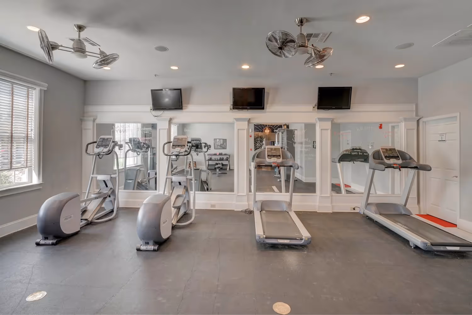Well-equipped fitness center at The Grand at Lake Sheri, Valdosta, GA, featuring treadmills, ellipticals, and weight machines for residents.