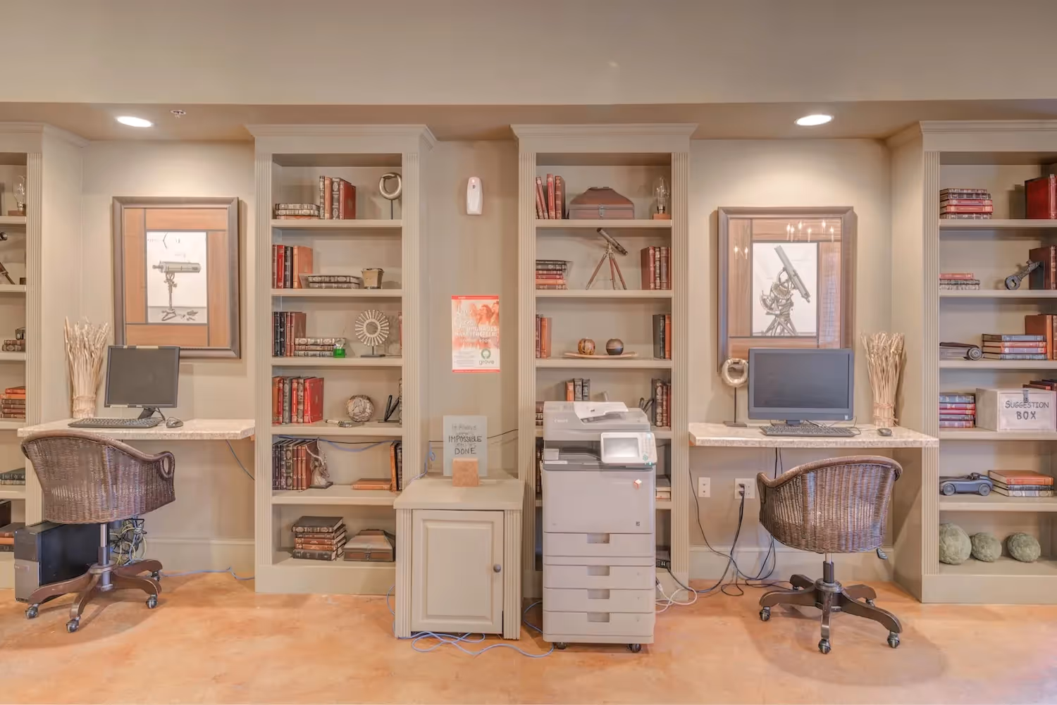 Business center at The Grand at Lake Sheri in Valdosta, GA, equipped with computers, printer, and bookshelves for resident use.