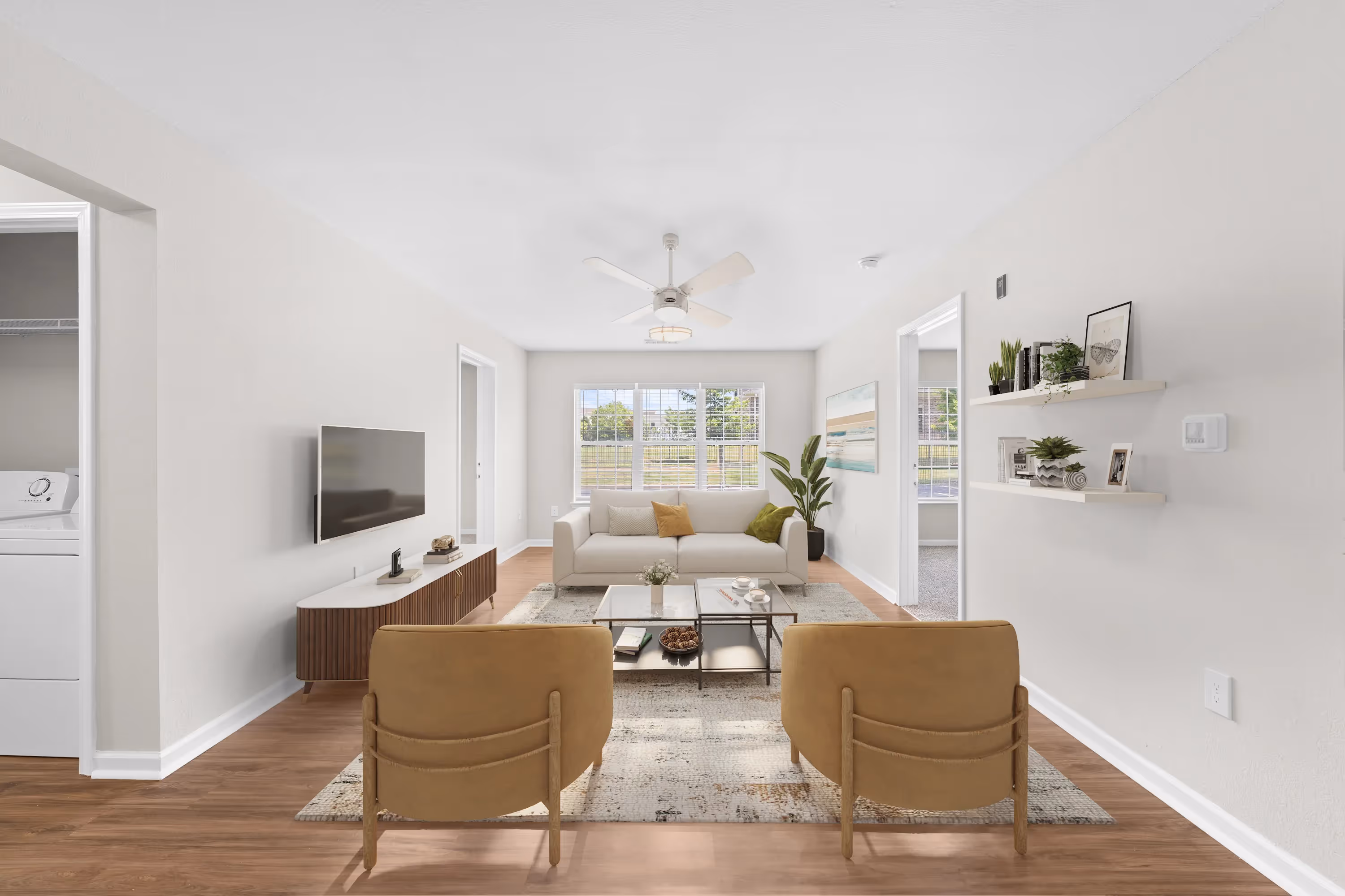 Inviting living room in an apartment at The Grand at Lake Sheri, Valdosta, GA, with wood-style flooring, a white sofa, and plenty of natural light.