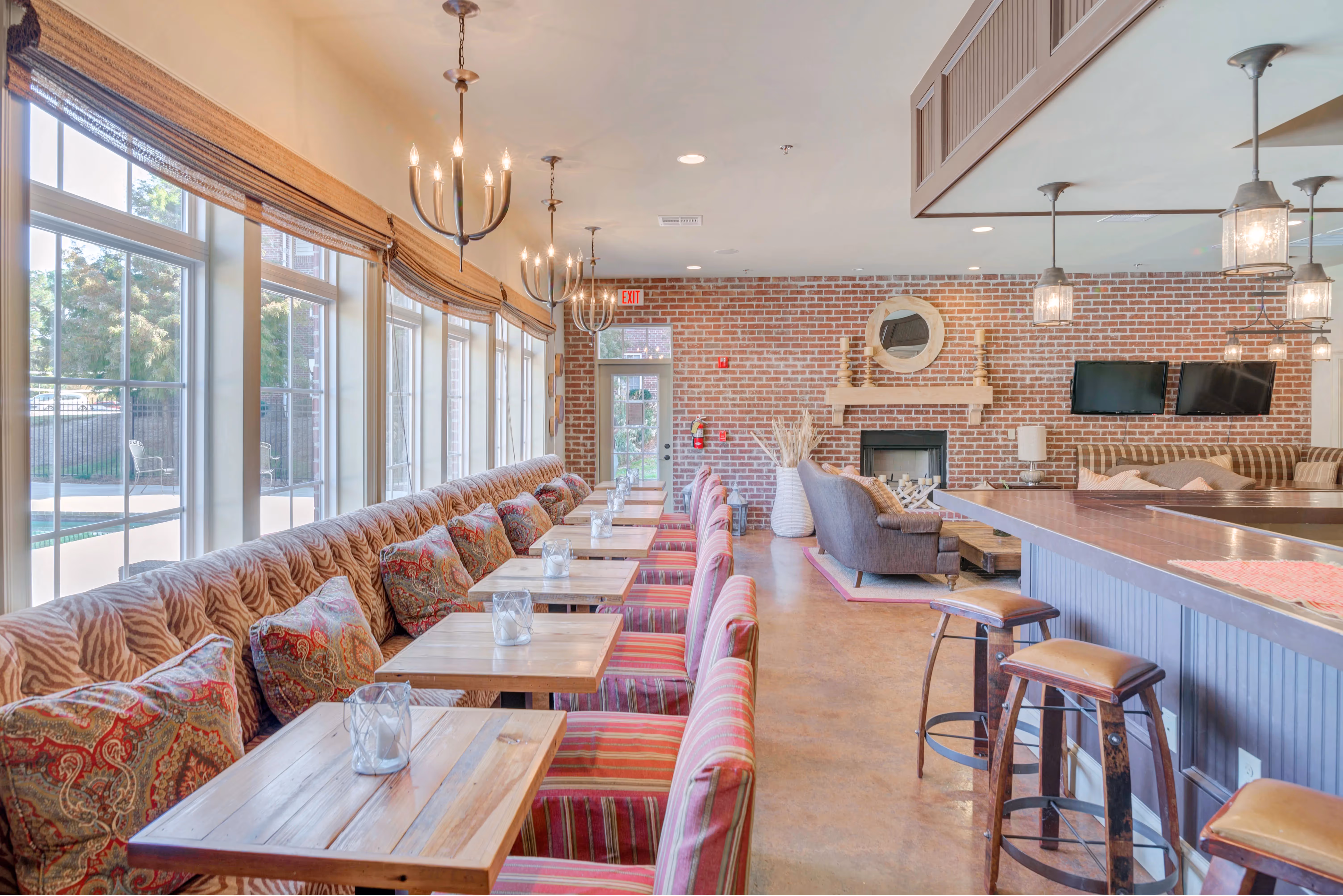 Spacious resident clubhouse dining and lounge area at The Grand at Lake Sheri in Valdosta, GA, with booth seating, tables, a fireplace, and a bar.