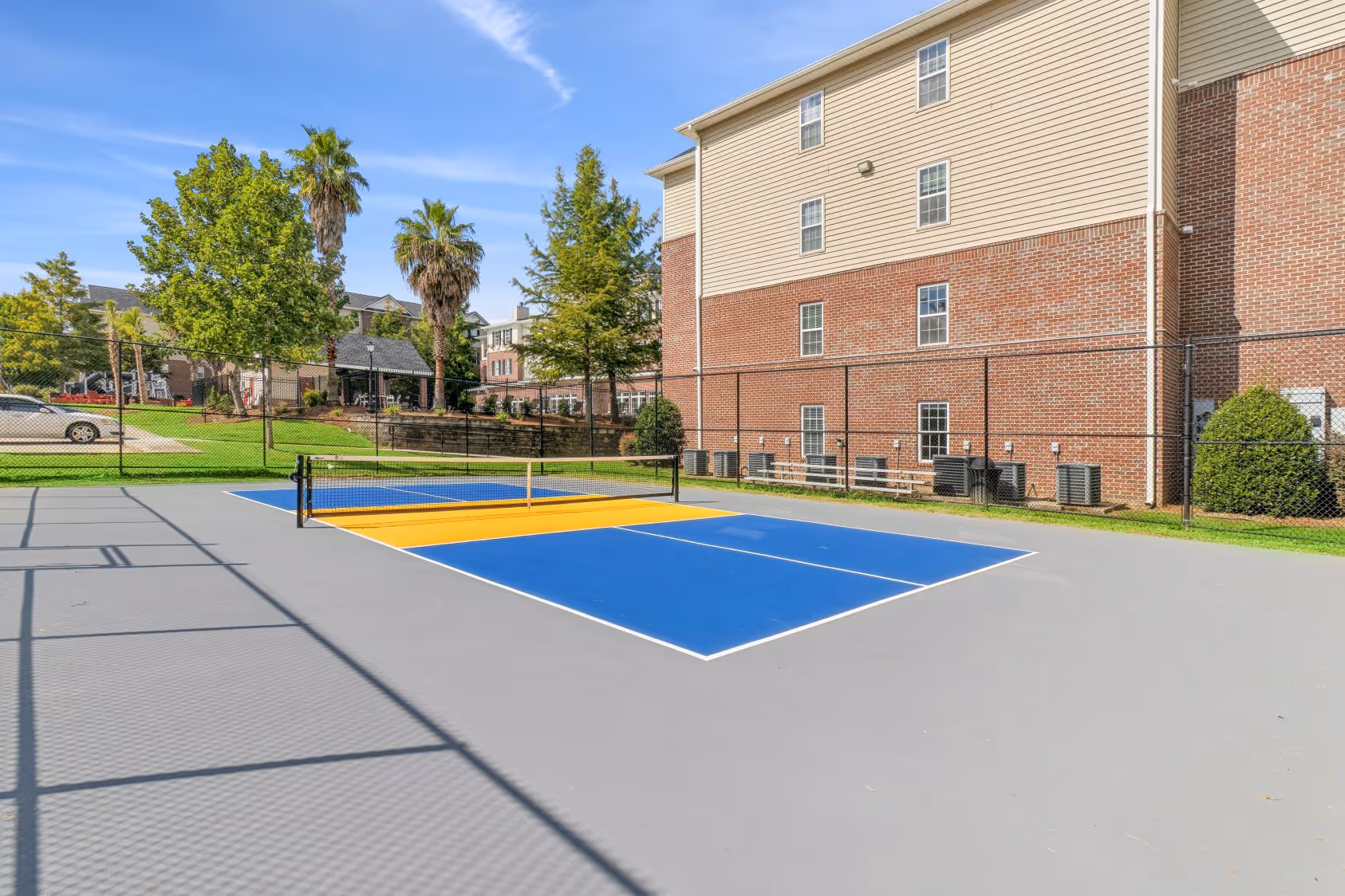 Aerial view of the outdoor basketball court and multi-story apartment buildings at The Grand at Lake Sheri, Valdosta, GA.