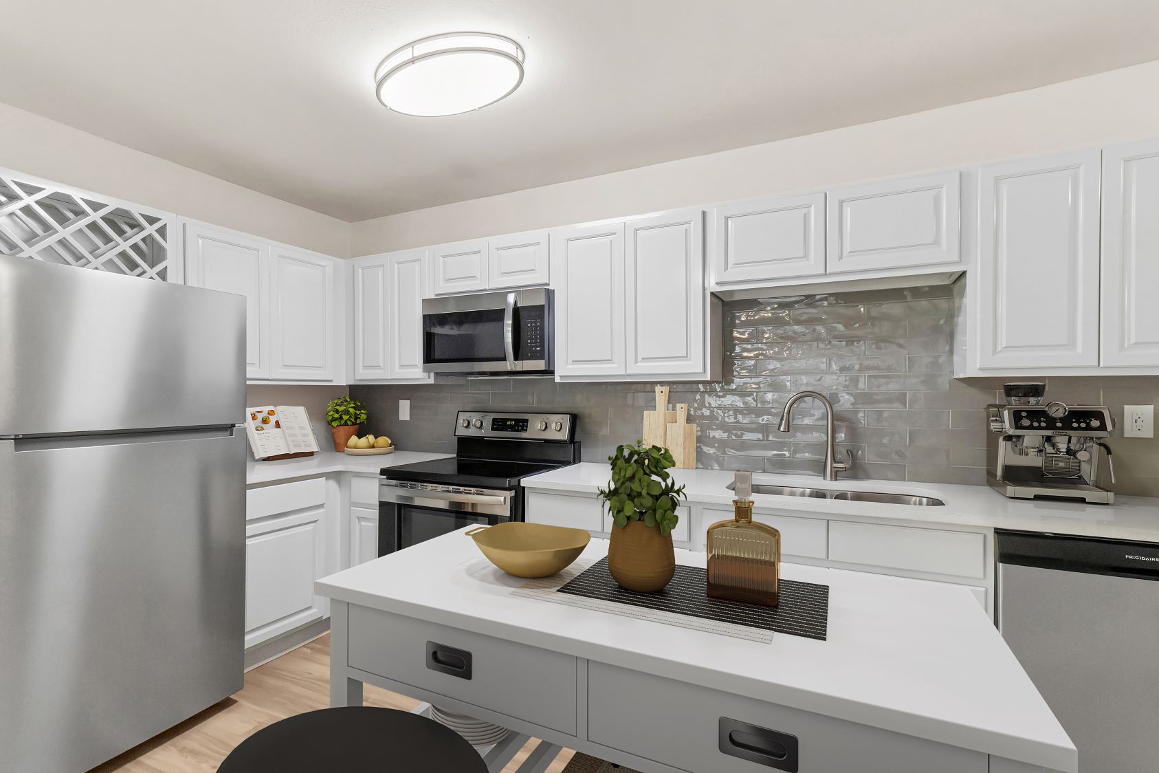 Bright apartment kitchen at The Grand at Lake Sheri, Valdosta, GA, featuring white shaker cabinets, granite countertops, subway tile backsplash, and a dining area.