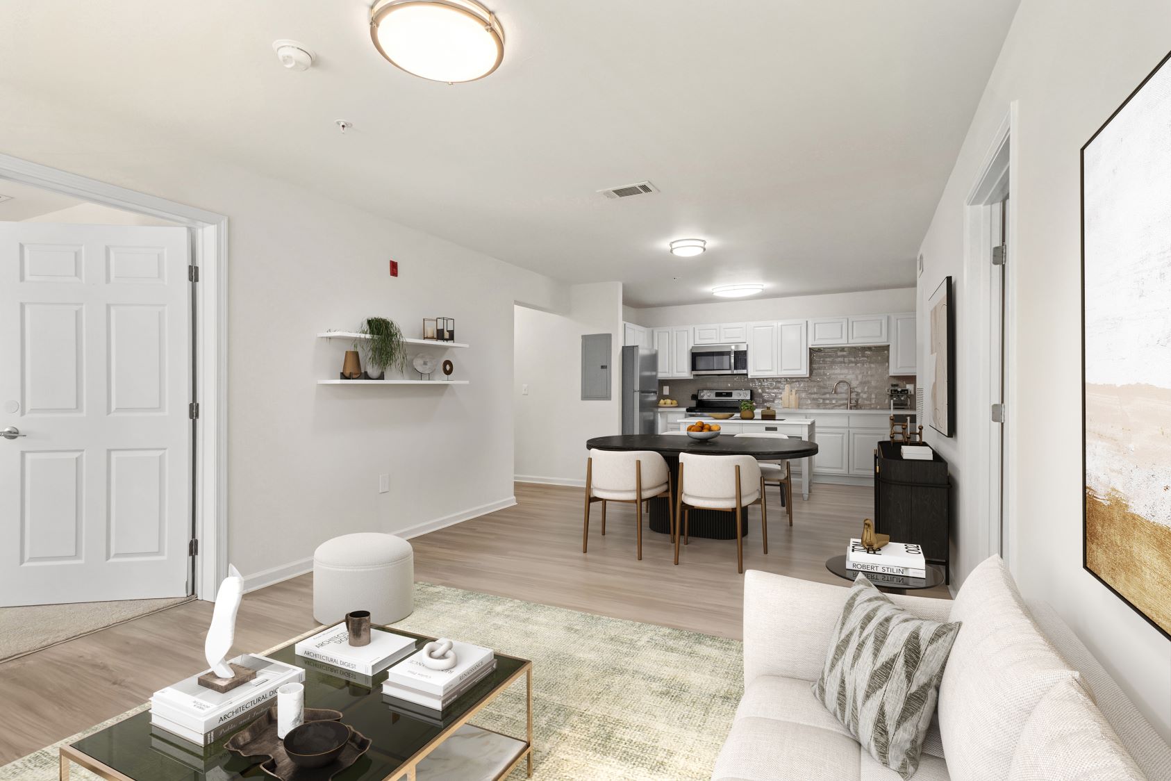 Inviting living room in an apartment at The Grand at Lake Sheri, Valdosta, GA, with wood-style flooring, a white sofa, and plenty of natural light.
