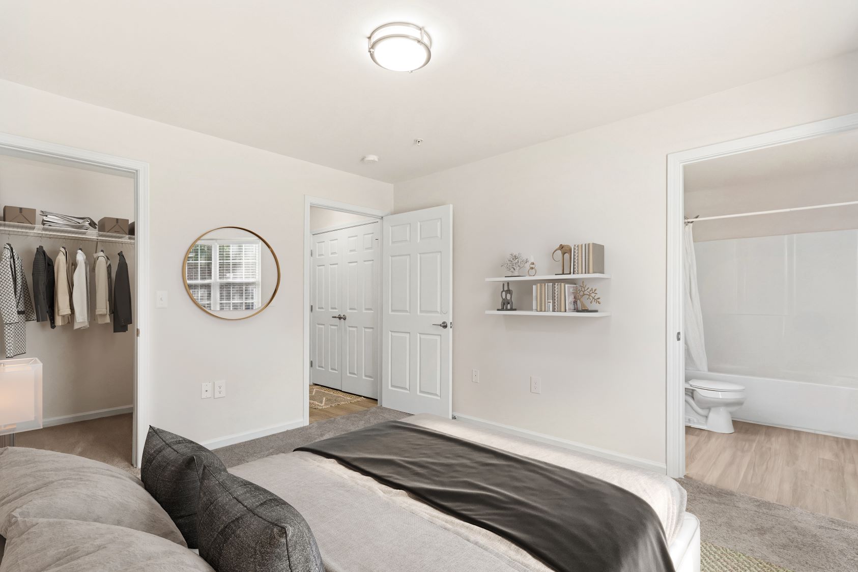 Bedroom in an apartment at The Grand at Lake Sheri, Valdosta, GA, featuring a large bed, ceiling fan, and access to a walk-in closet and bathroom.