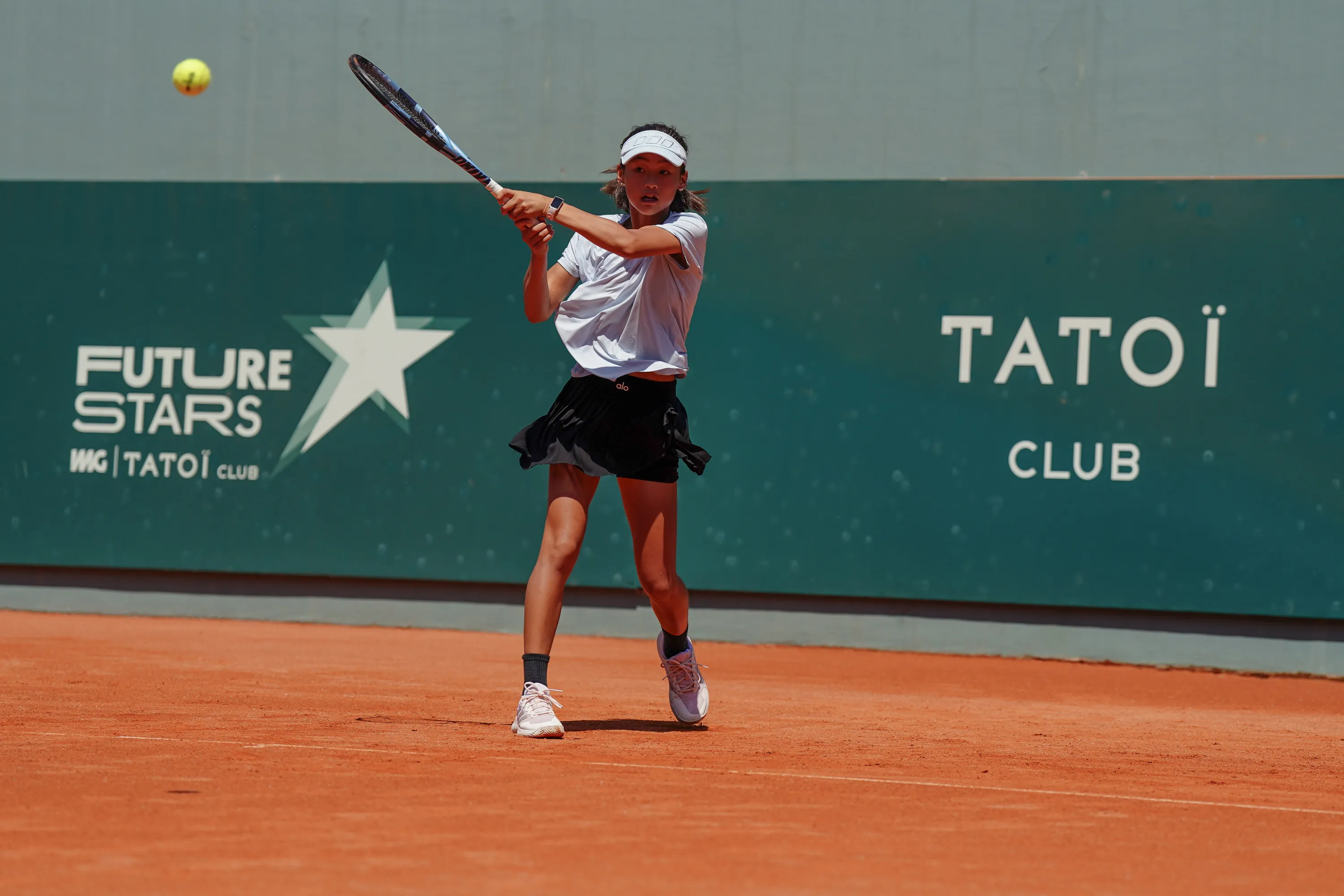 Tatiana Na hitting a backhand on clay at a European junior event with the Lavie Tour Team