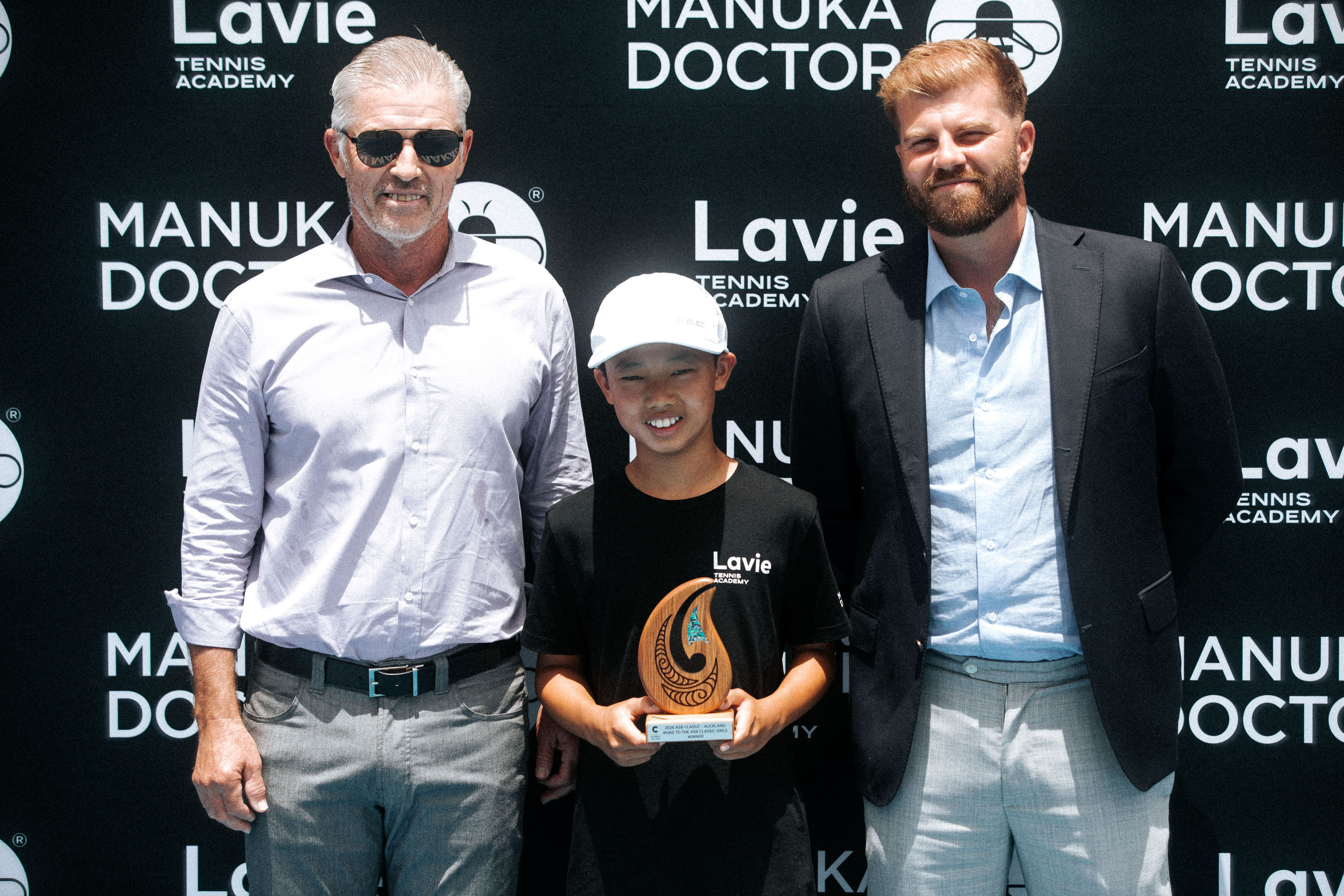 Road to the ASB Classic winner with his trophy in front of the Manuka Doctor and Lavie Tennis Academy wall